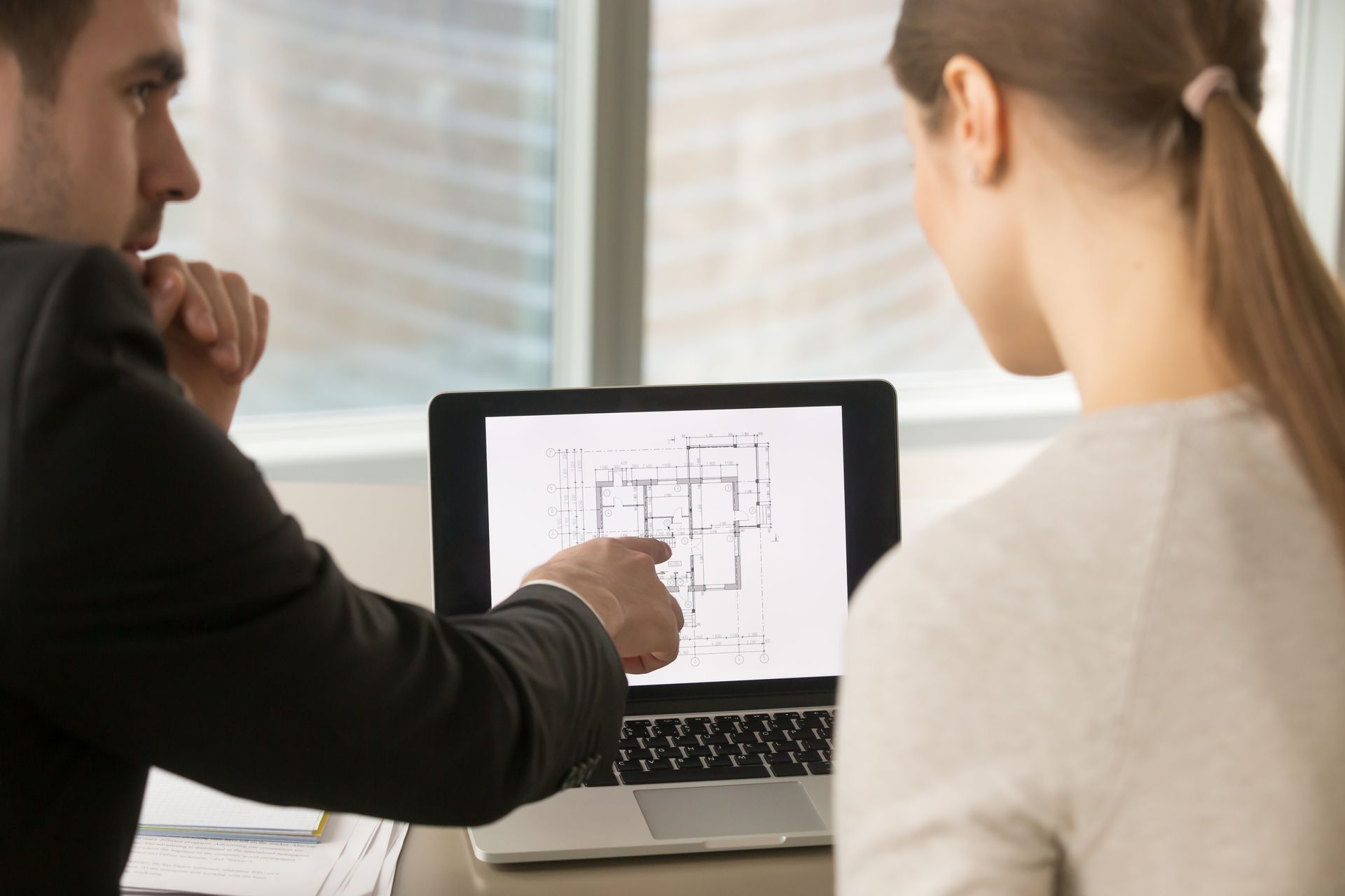 A man and a woman are looking at a laptop computer.