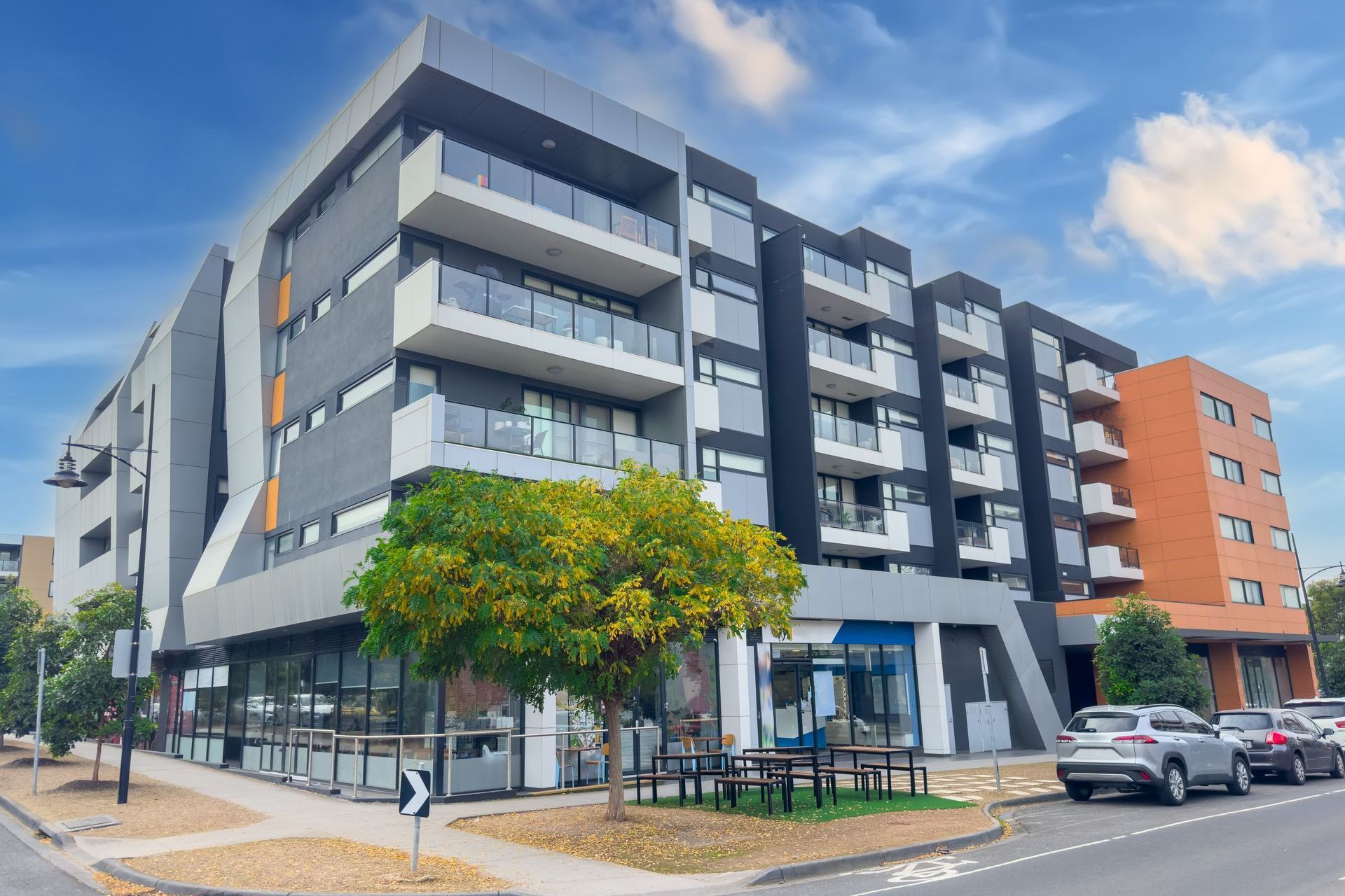 A large apartment building with cars parked in front of it.