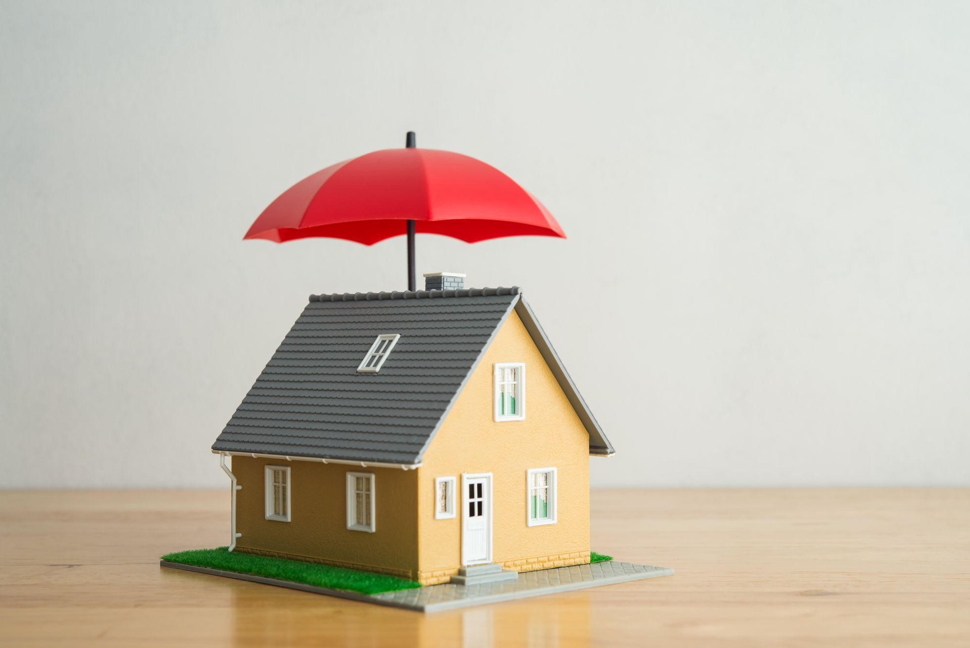 A model house with a red umbrella on top of it.