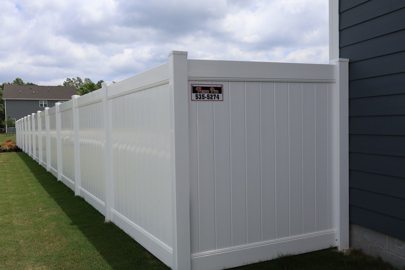 A long white fence is sitting next to a house.