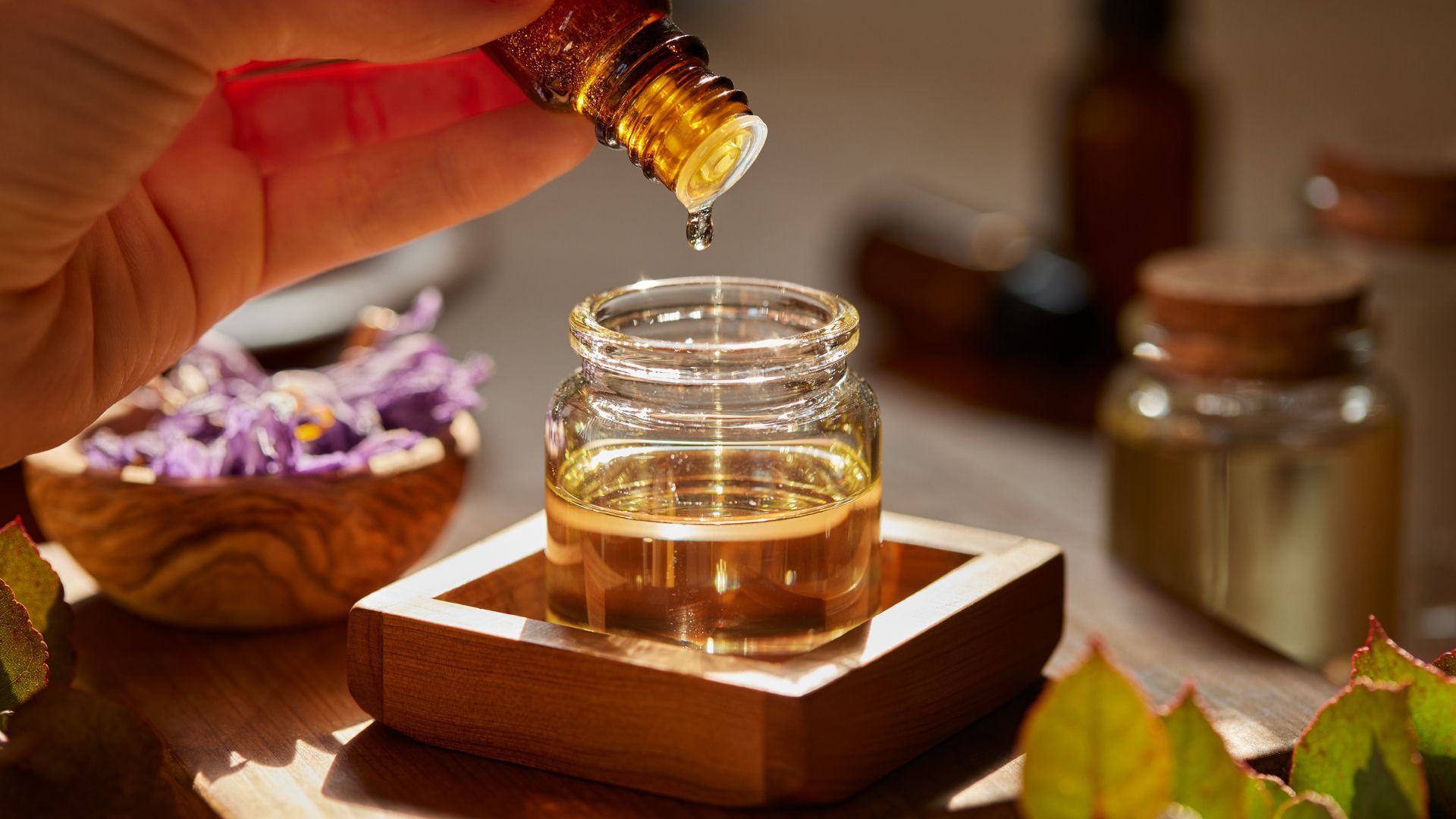 A person is pouring essential oil into a small glass jar.