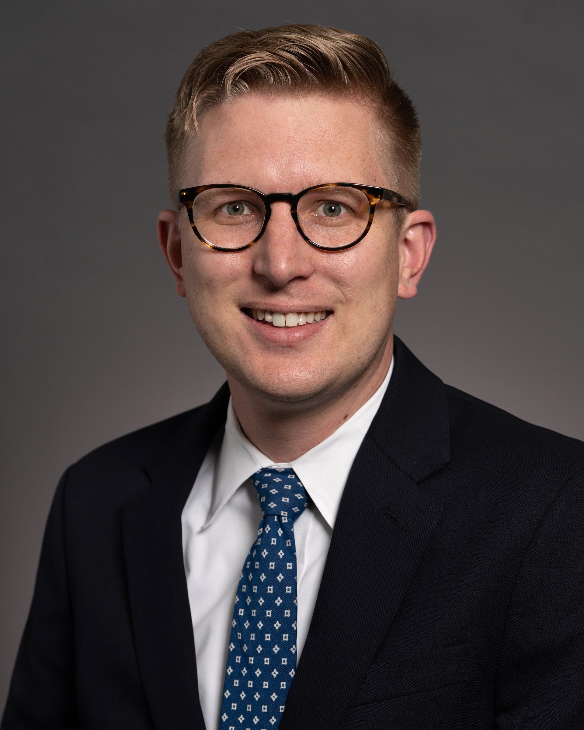 A man in a suit and tie is smiling for the camera.