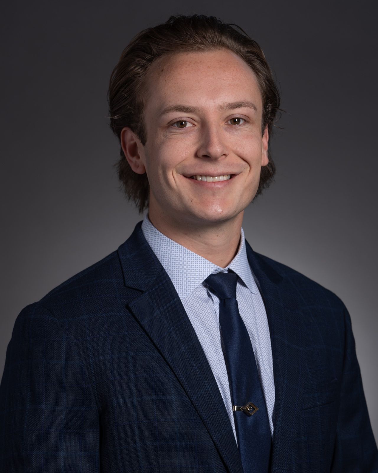 A young man in a suit and tie is smiling for the camera.