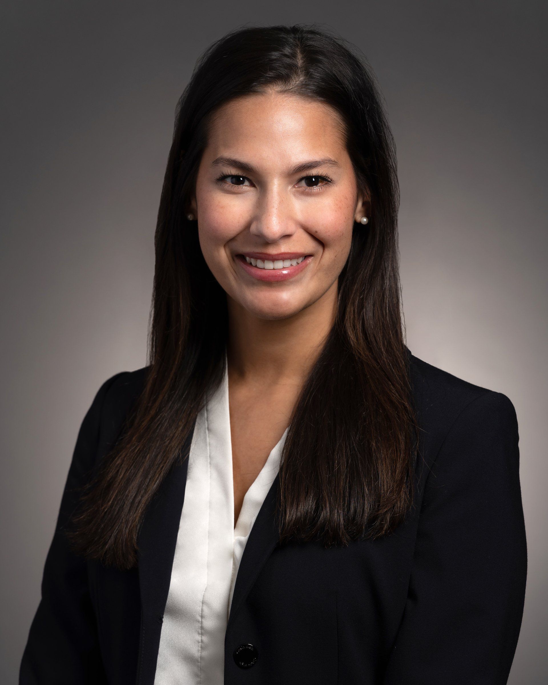 A woman in a black jacket and white shirt is smiling for the camera.