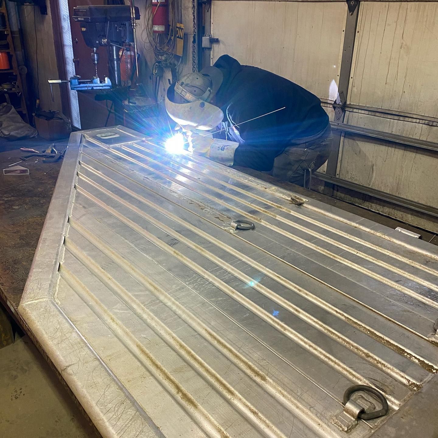 A man is welding a piece of metal in a garage.