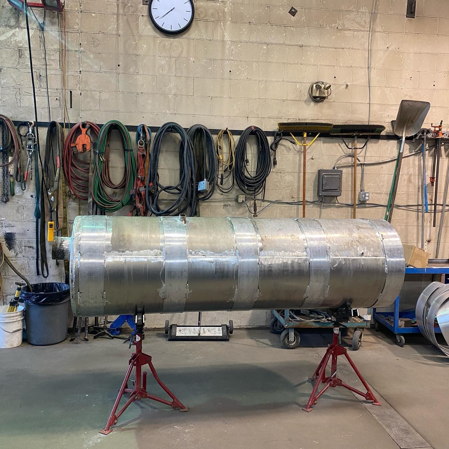 A large metal pipe is sitting on a stand in a workshop