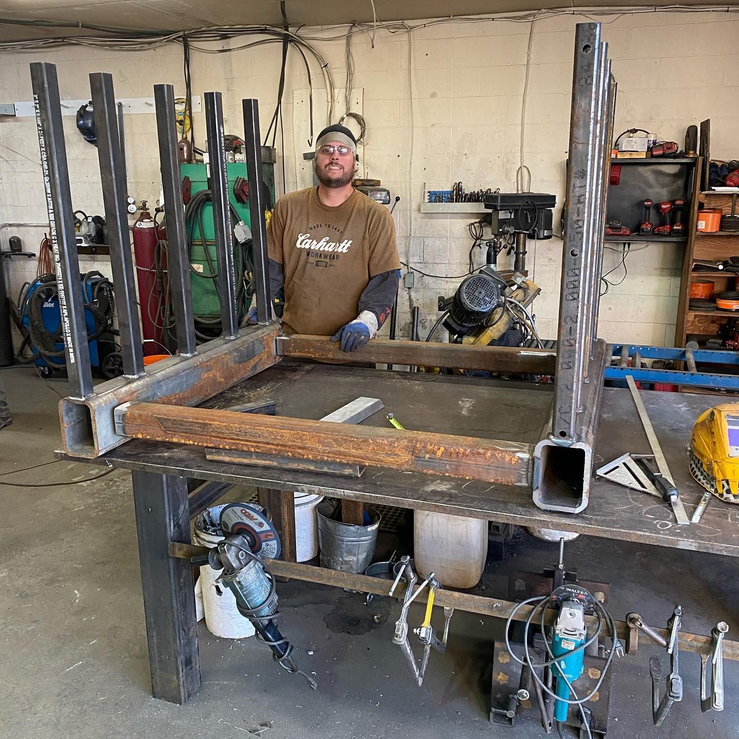 A man is standing in front of a table in a workshop.