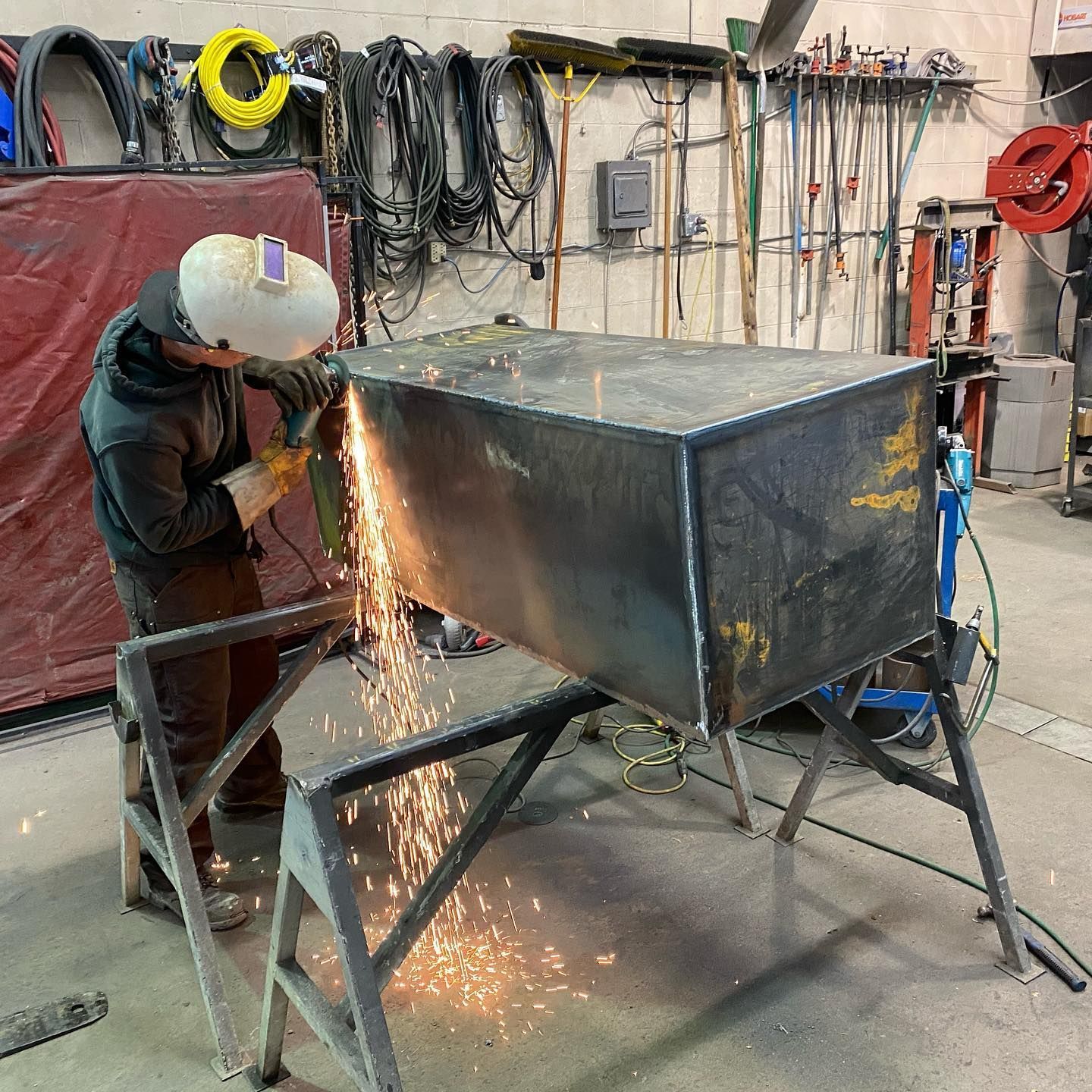A man is cutting a piece of metal with a grinder.