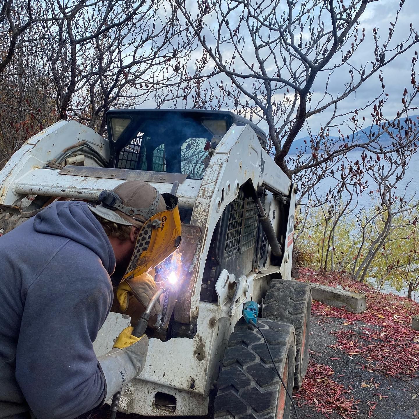A man is welding a piece of equipment outside