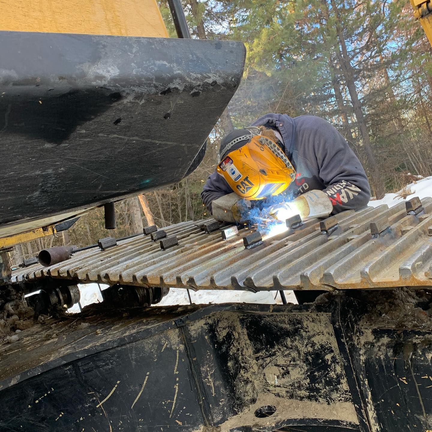 A man wearing a welding mask is welding a piece of metal.