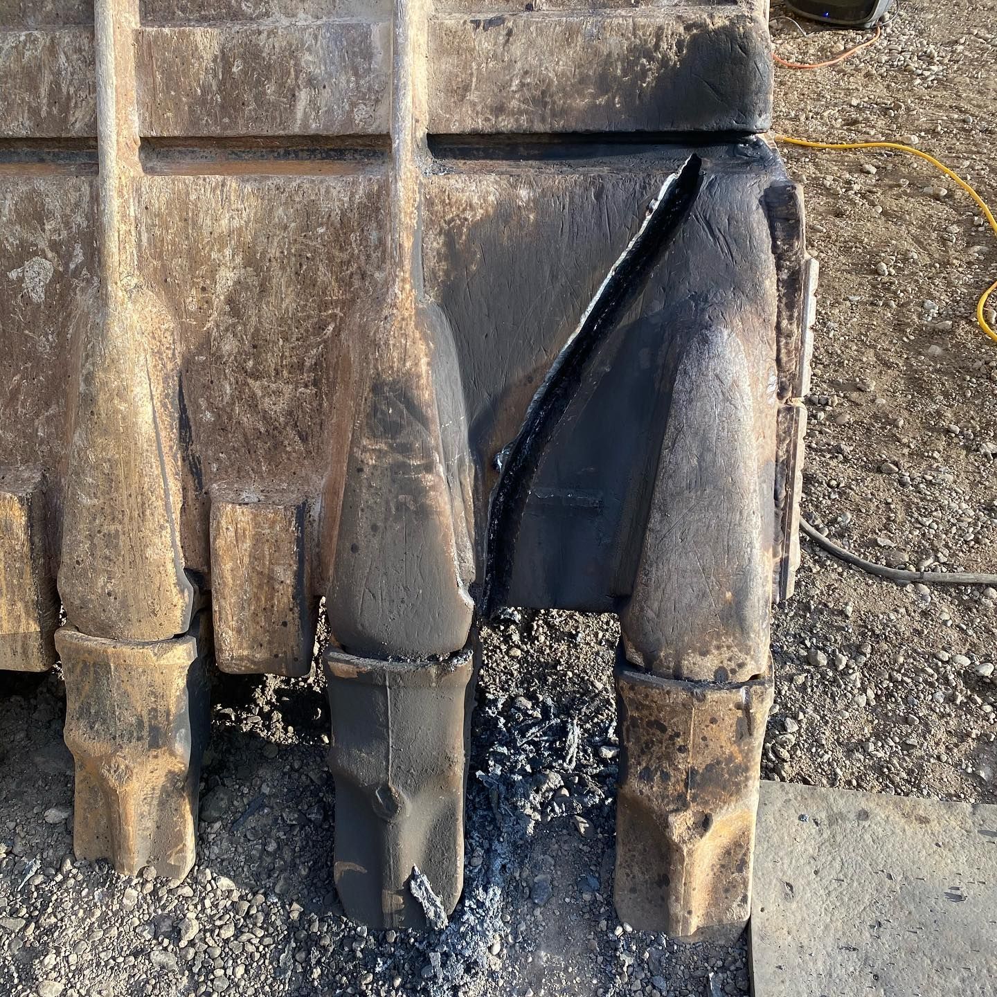 A close up of an excavator bucket with a hole in it