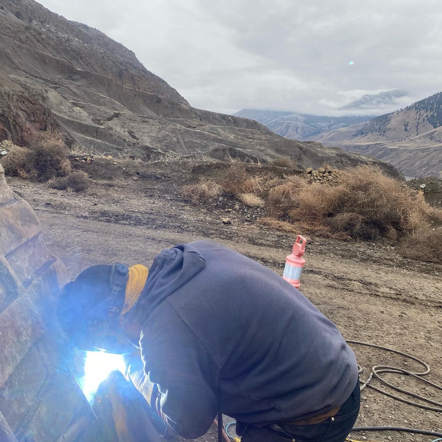 A man is welding a piece of metal in the desert