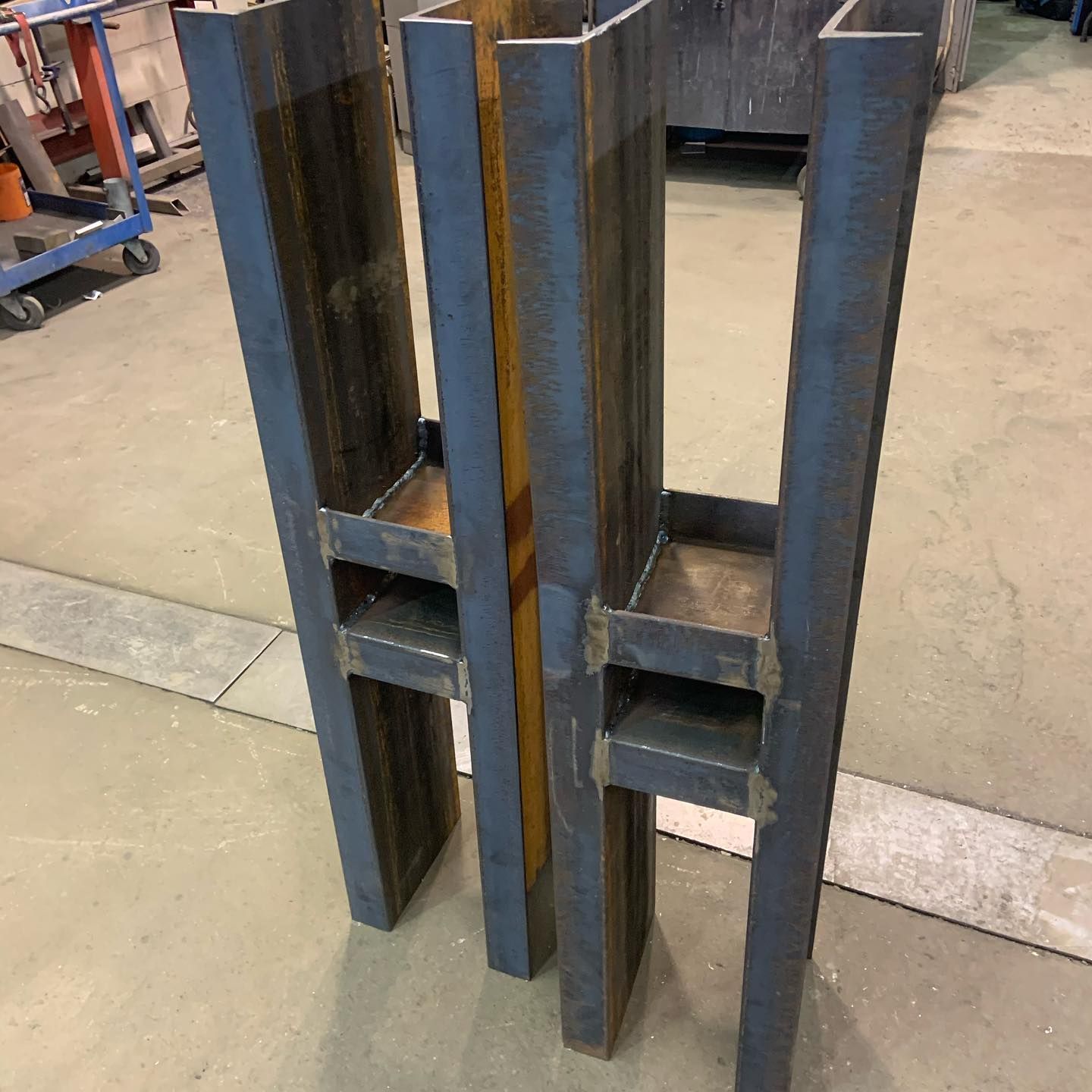 A pair of metal pillars sitting on top of a cement floor.