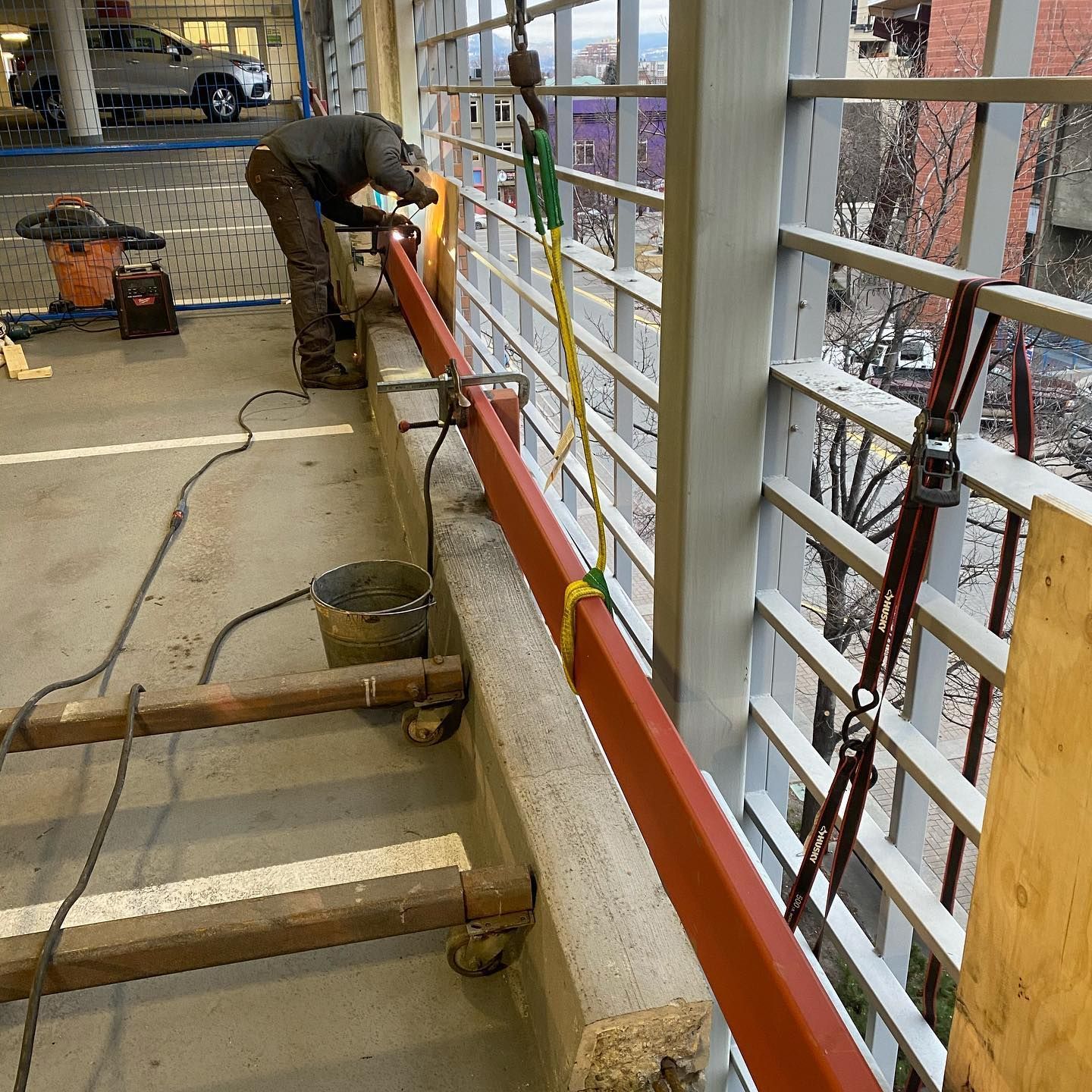 A man is welding a railing in a parking garage