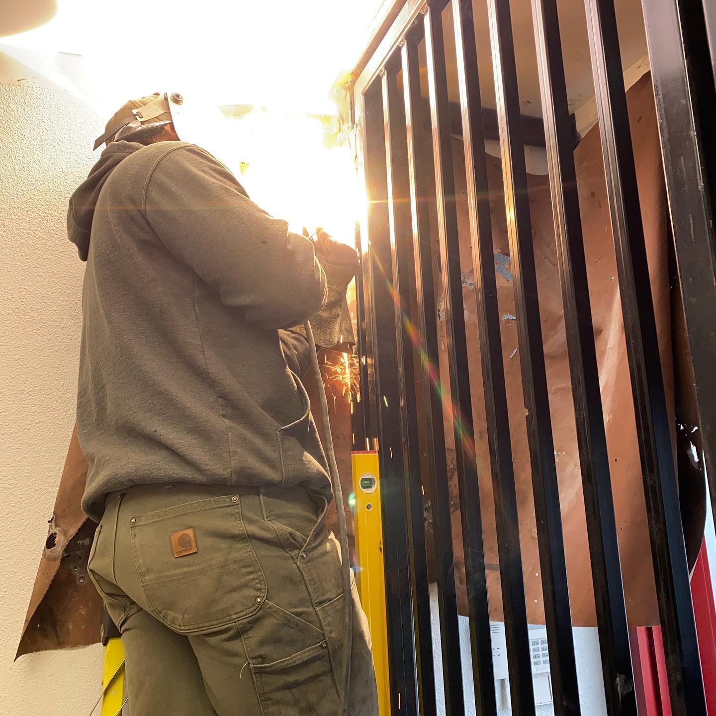 A man wearing a helmet is working on a railing