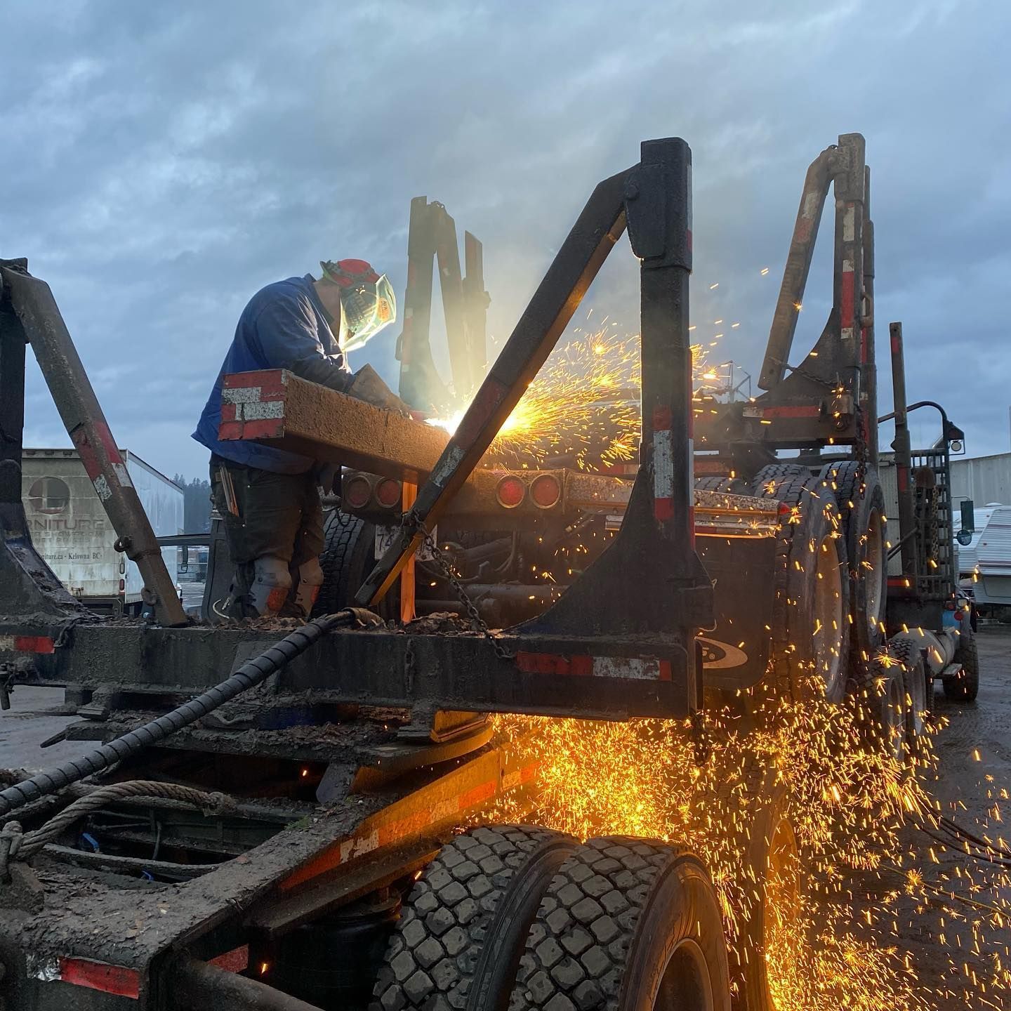 A man is welding on the back of a truck.