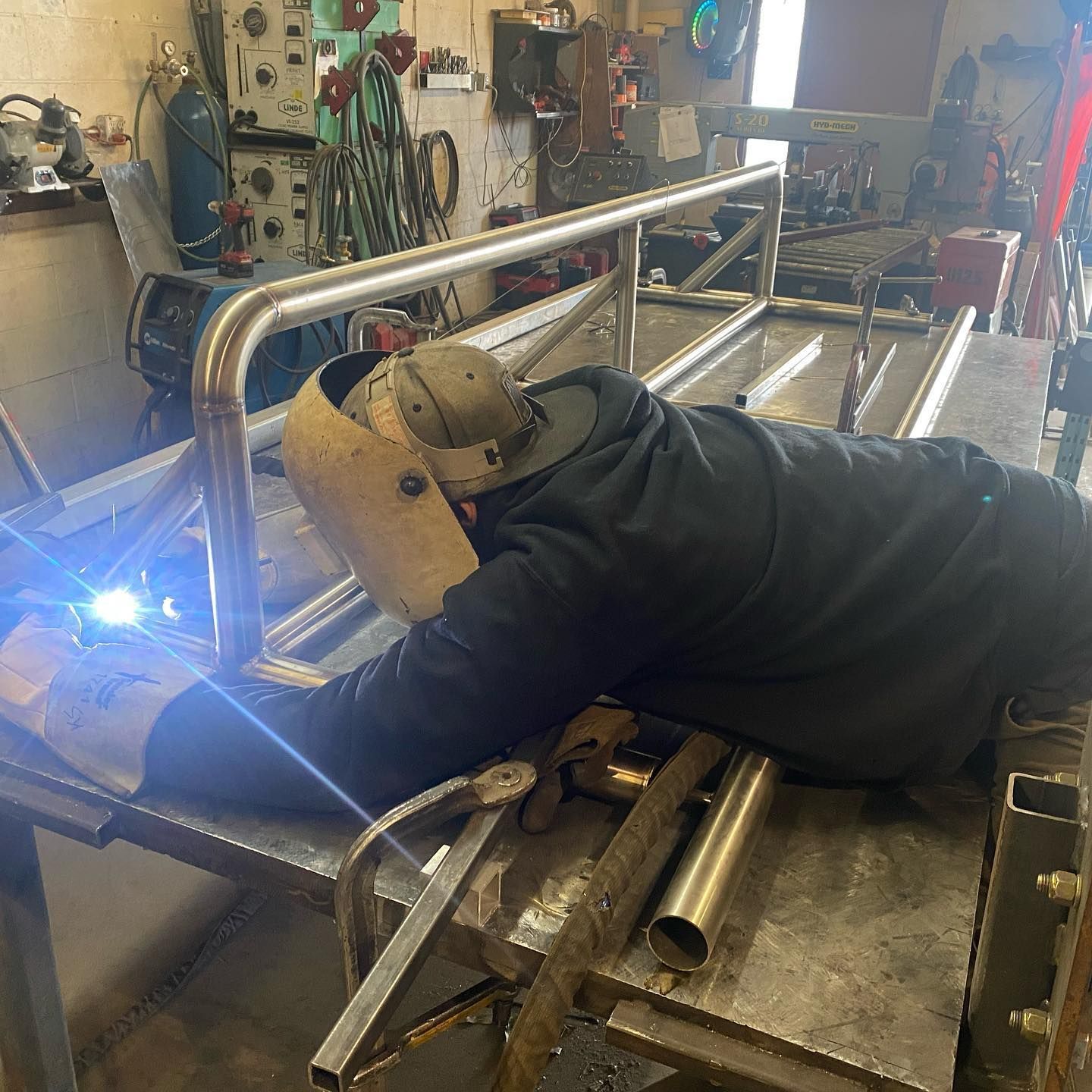 A man is laying on a table welding a metal railing.