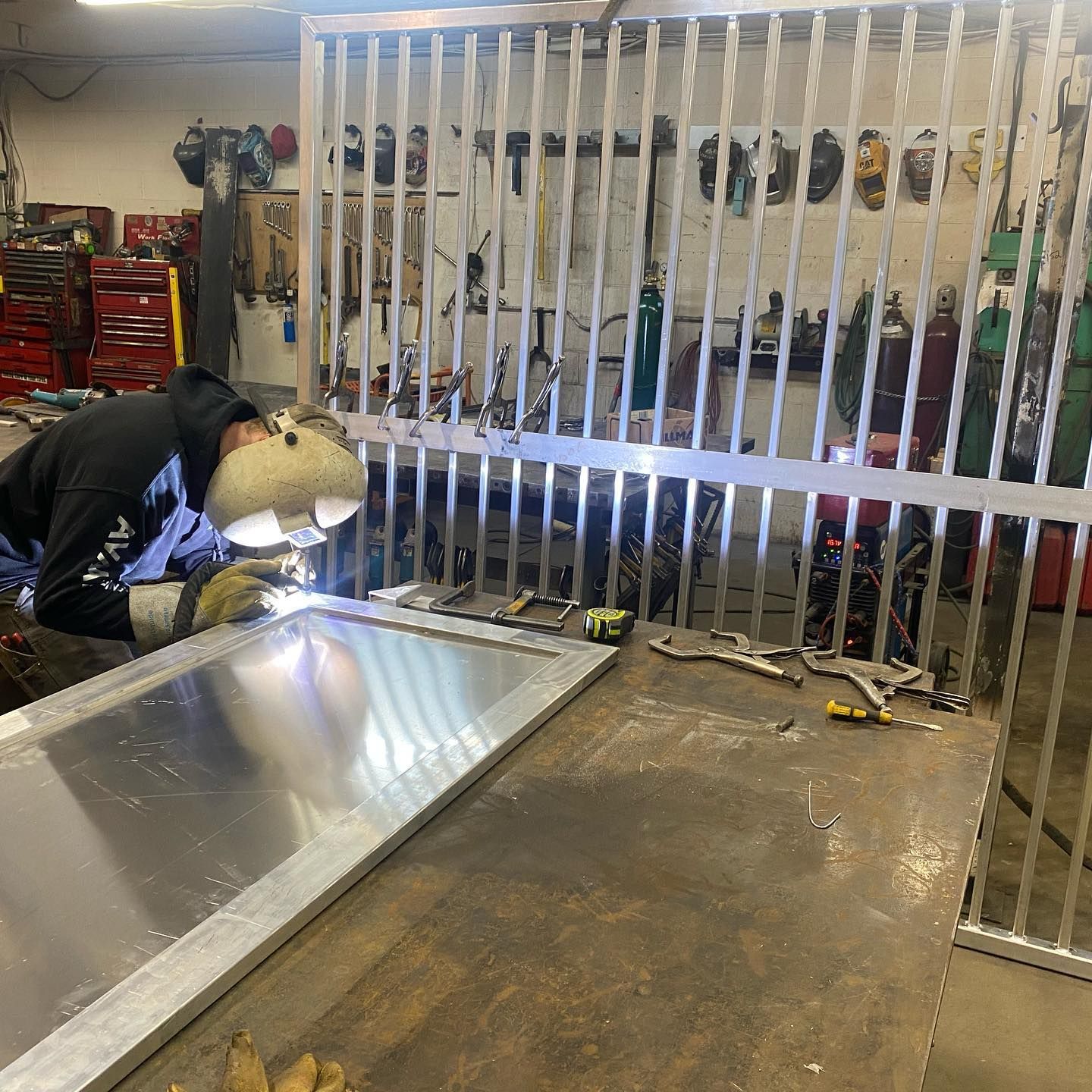 A man is welding a piece of metal in a workshop.