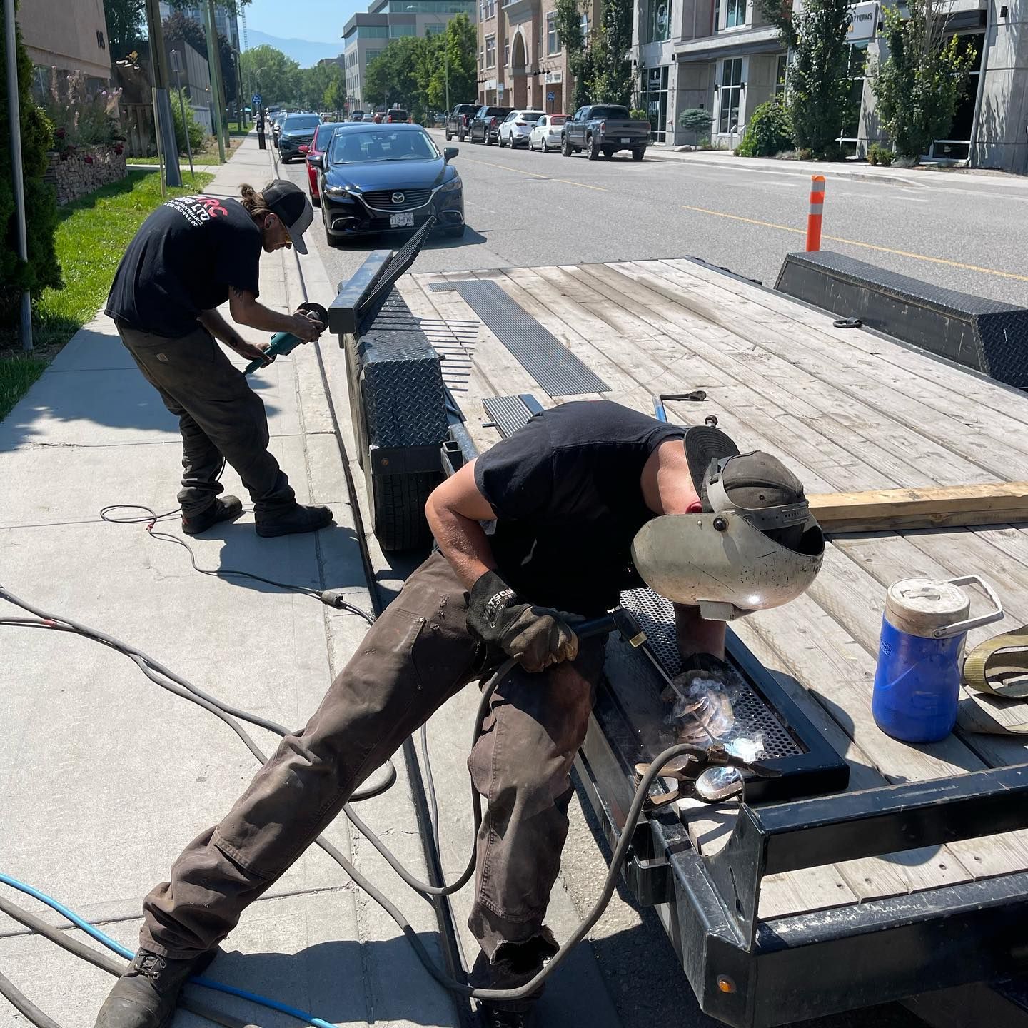 Two men are working on a trailer on the side of the road