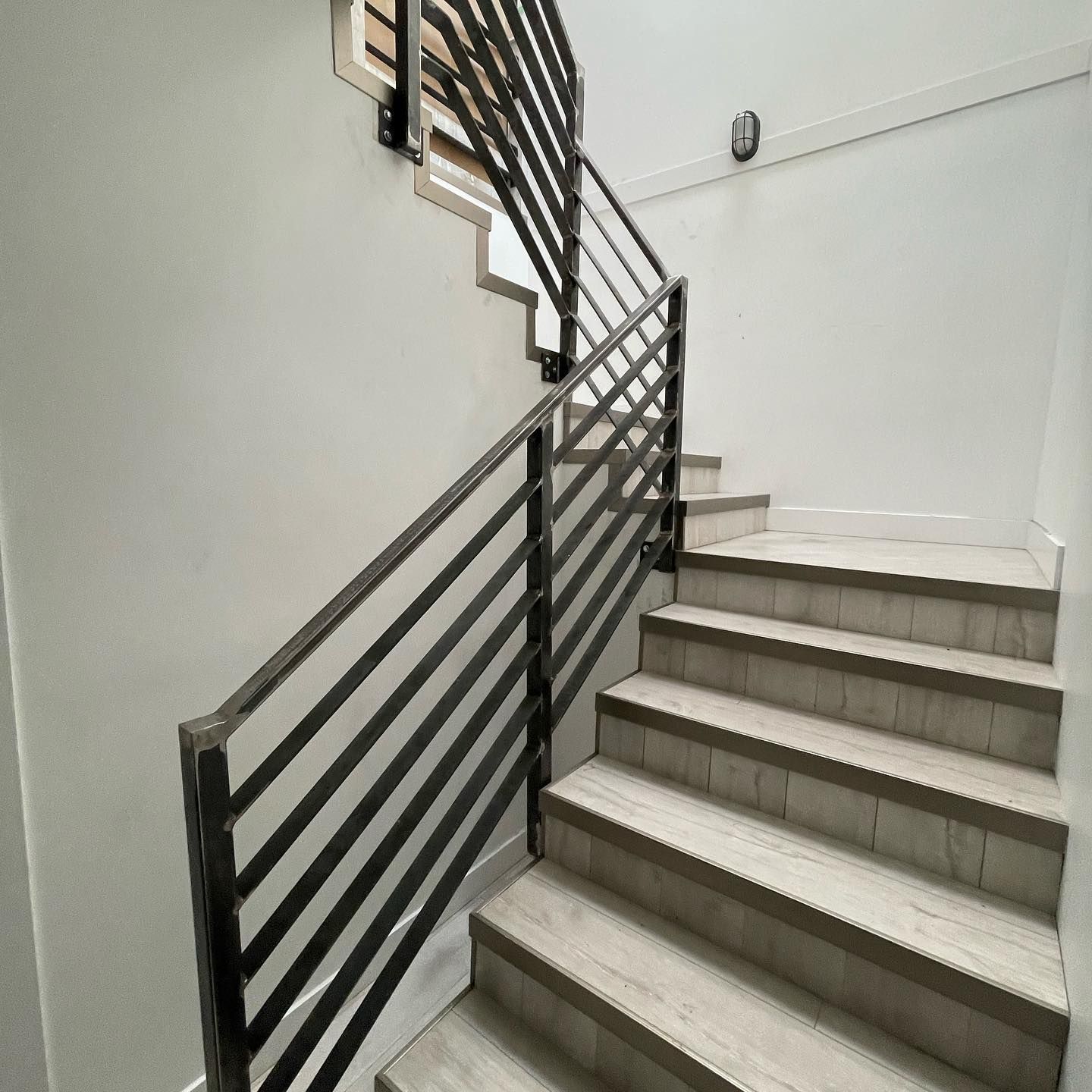 A set of stairs with a metal railing and a clock on the wall.