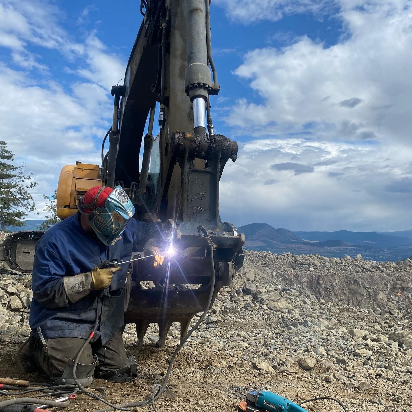 A man wearing a mask is welding a piece of equipment