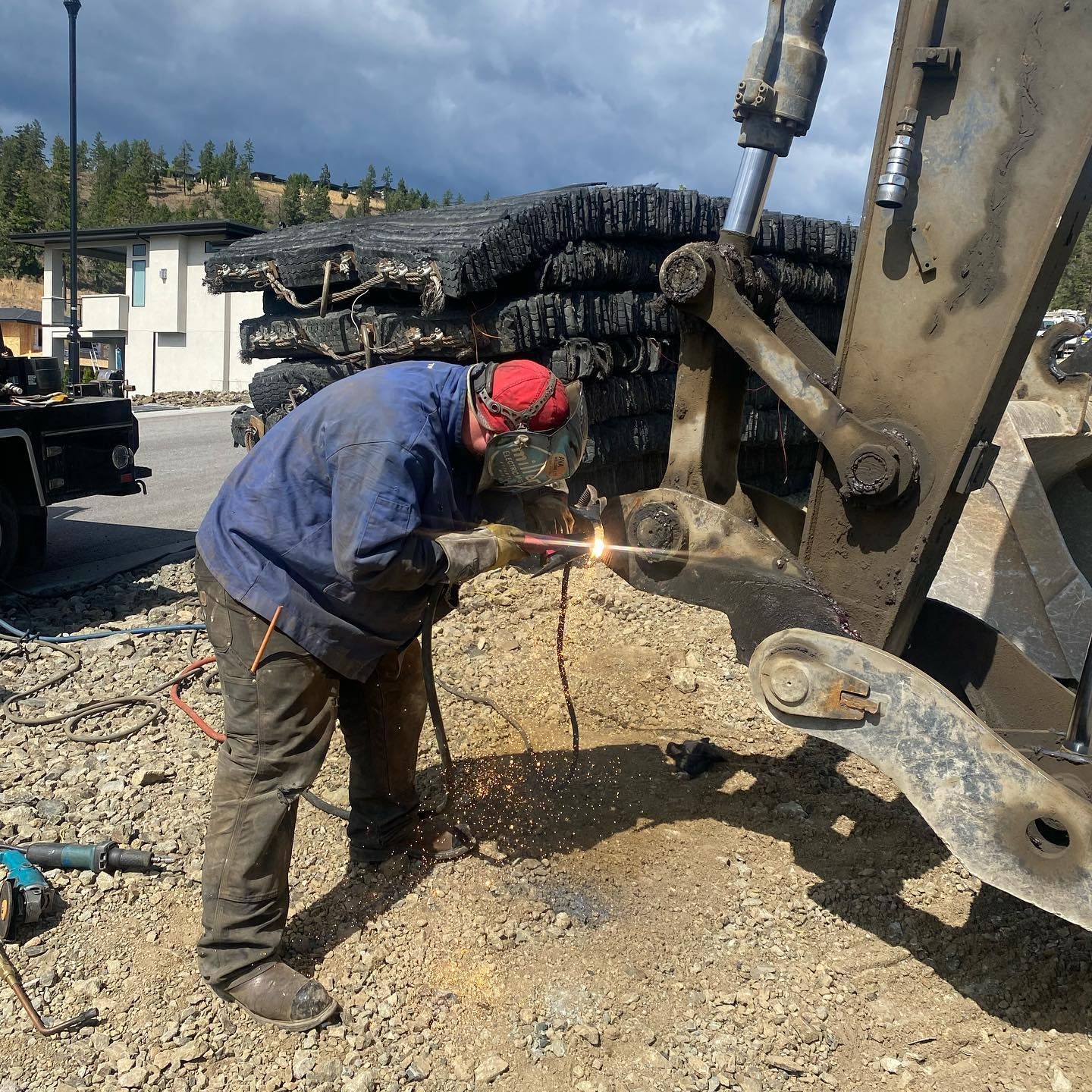 A man is welding a piece of metal in the dirt
