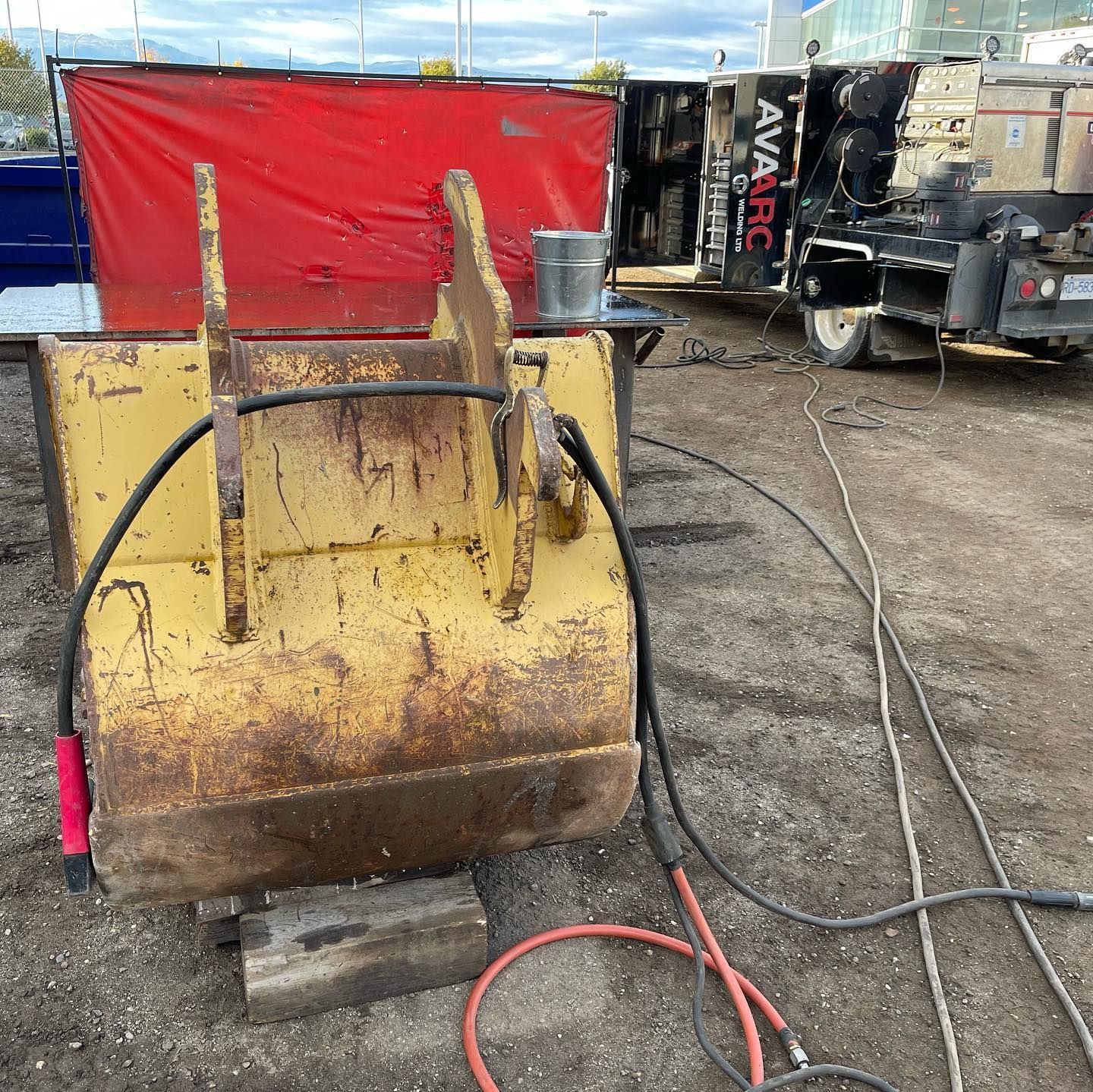 A bulldozer bucket with a hose attached to it