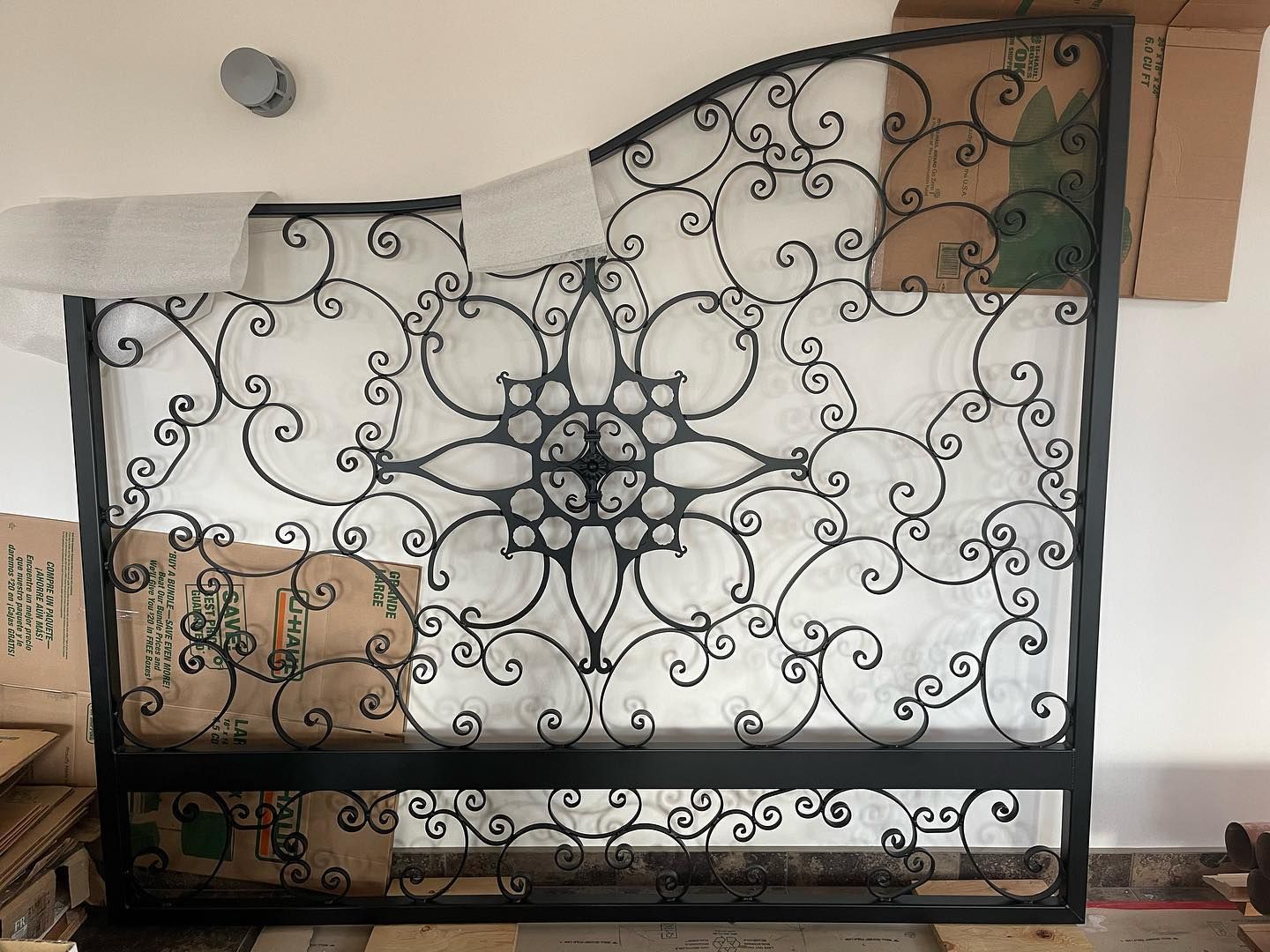 A wrought iron gate is sitting on top of a pile of cardboard boxes.