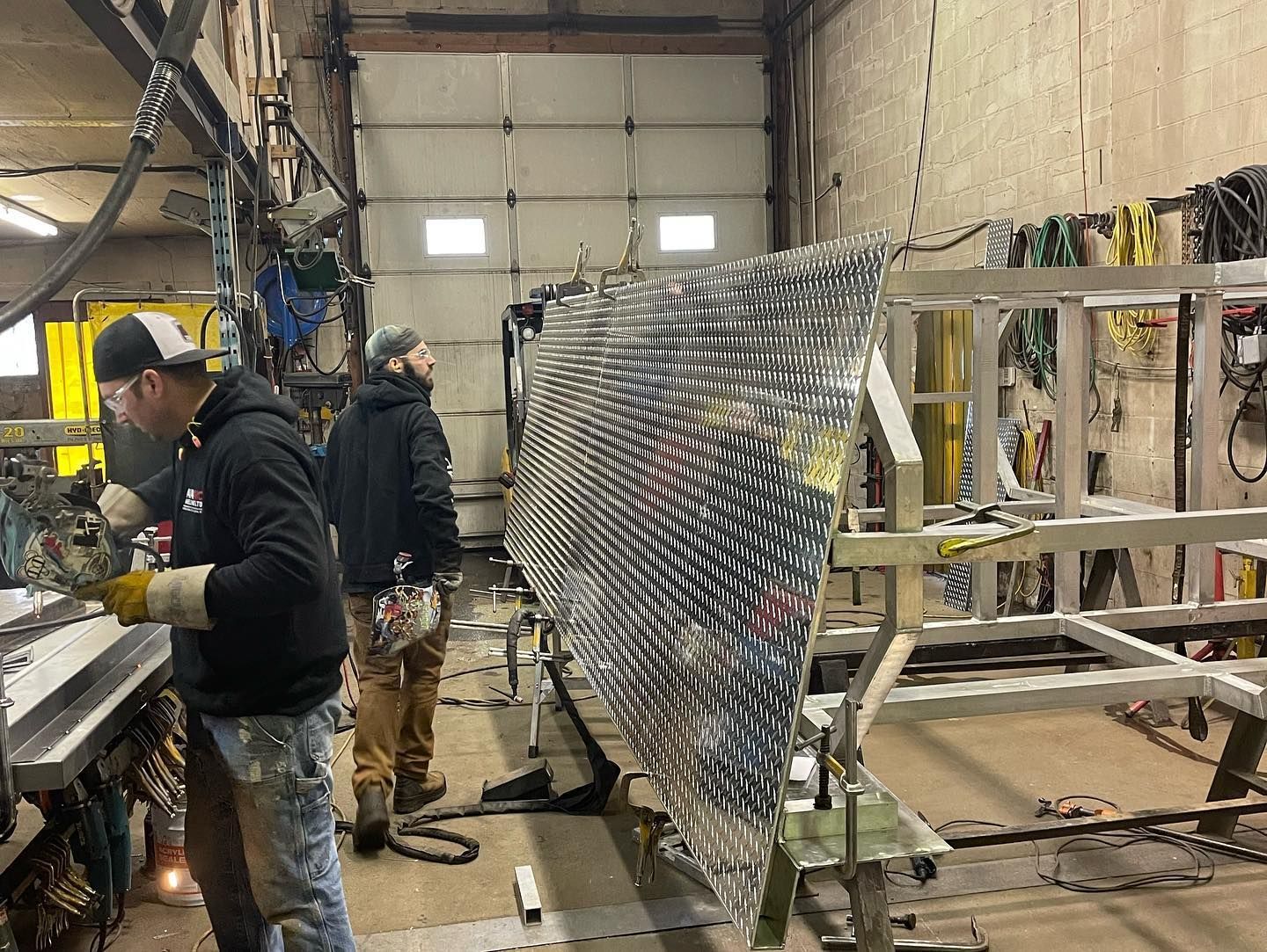 A group of men are working on a large piece of metal in a garage.