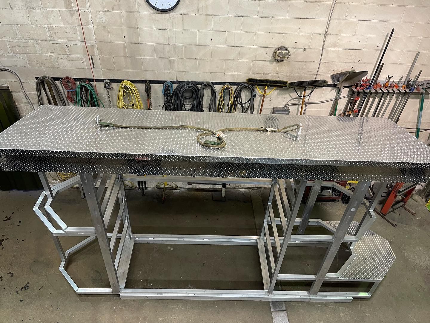 A metal workbench is sitting in a garage next to a clock.