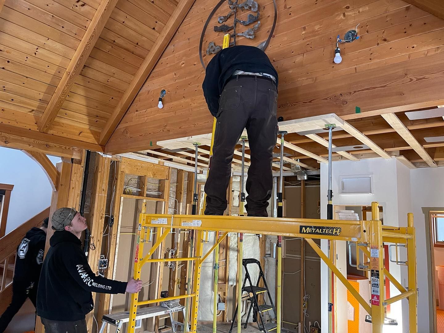 A man is standing on a yellow scaffolding in a room
