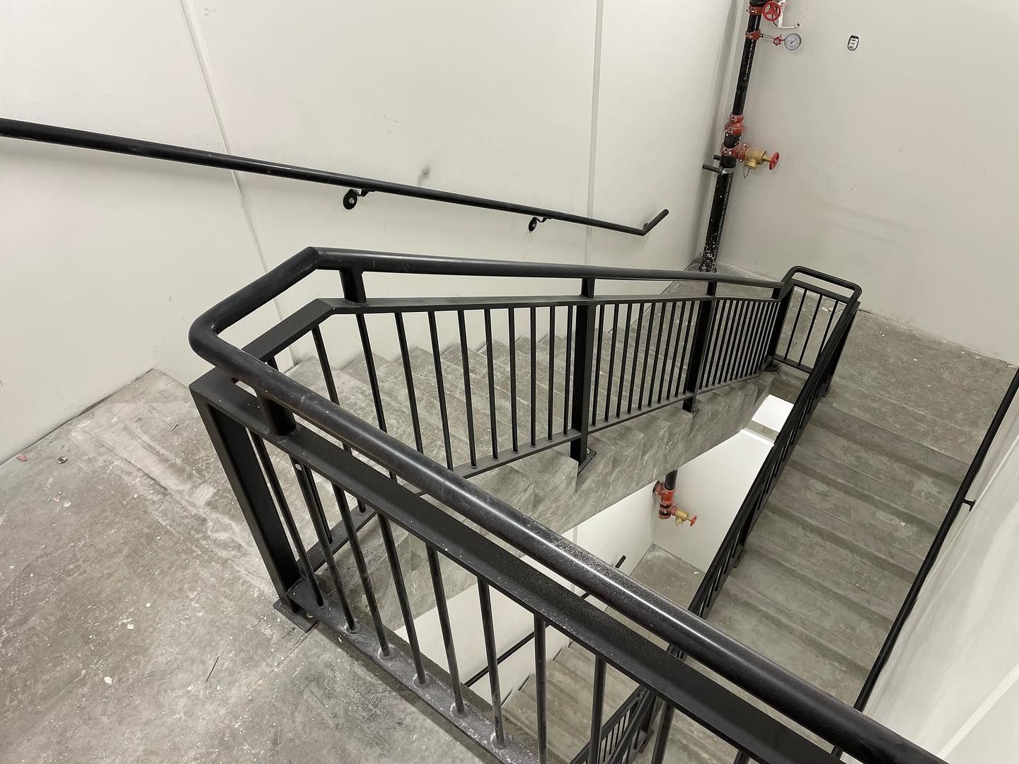 A staircase with a black railing is going up and down in a building.
