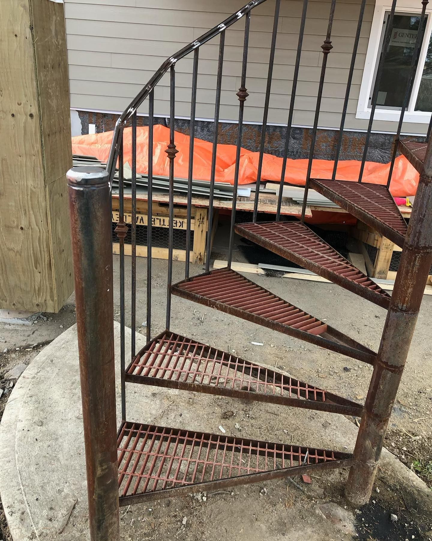 A rusty spiral staircase is sitting on top of a concrete platform.