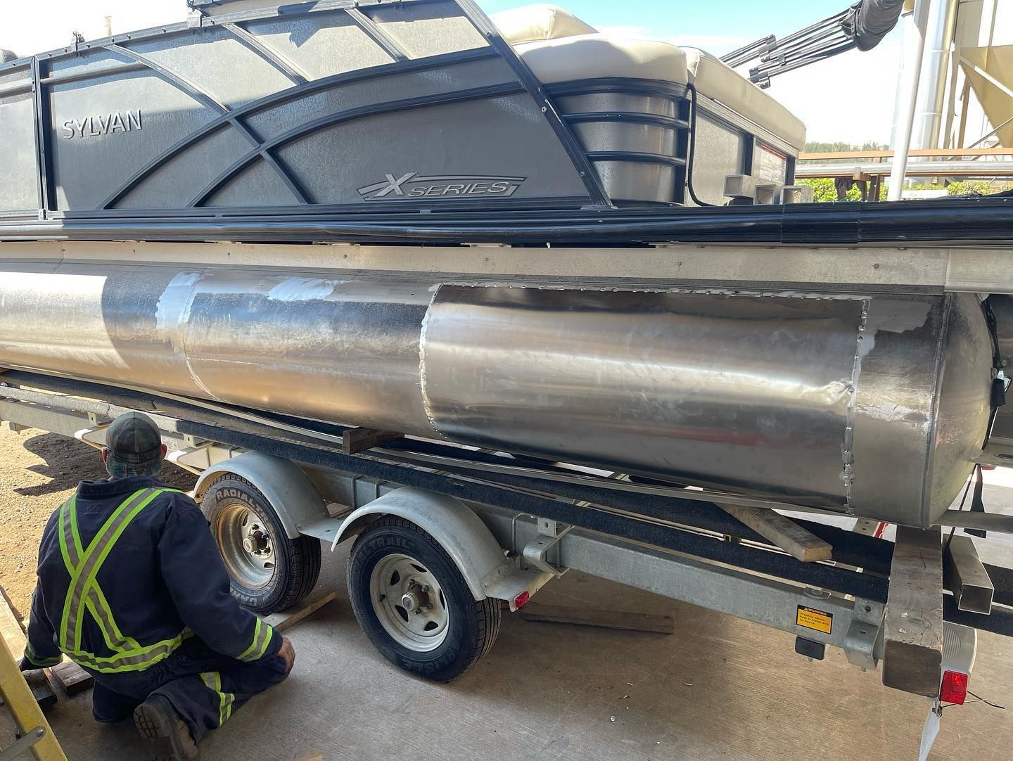 A man is working on a boat on a trailer.