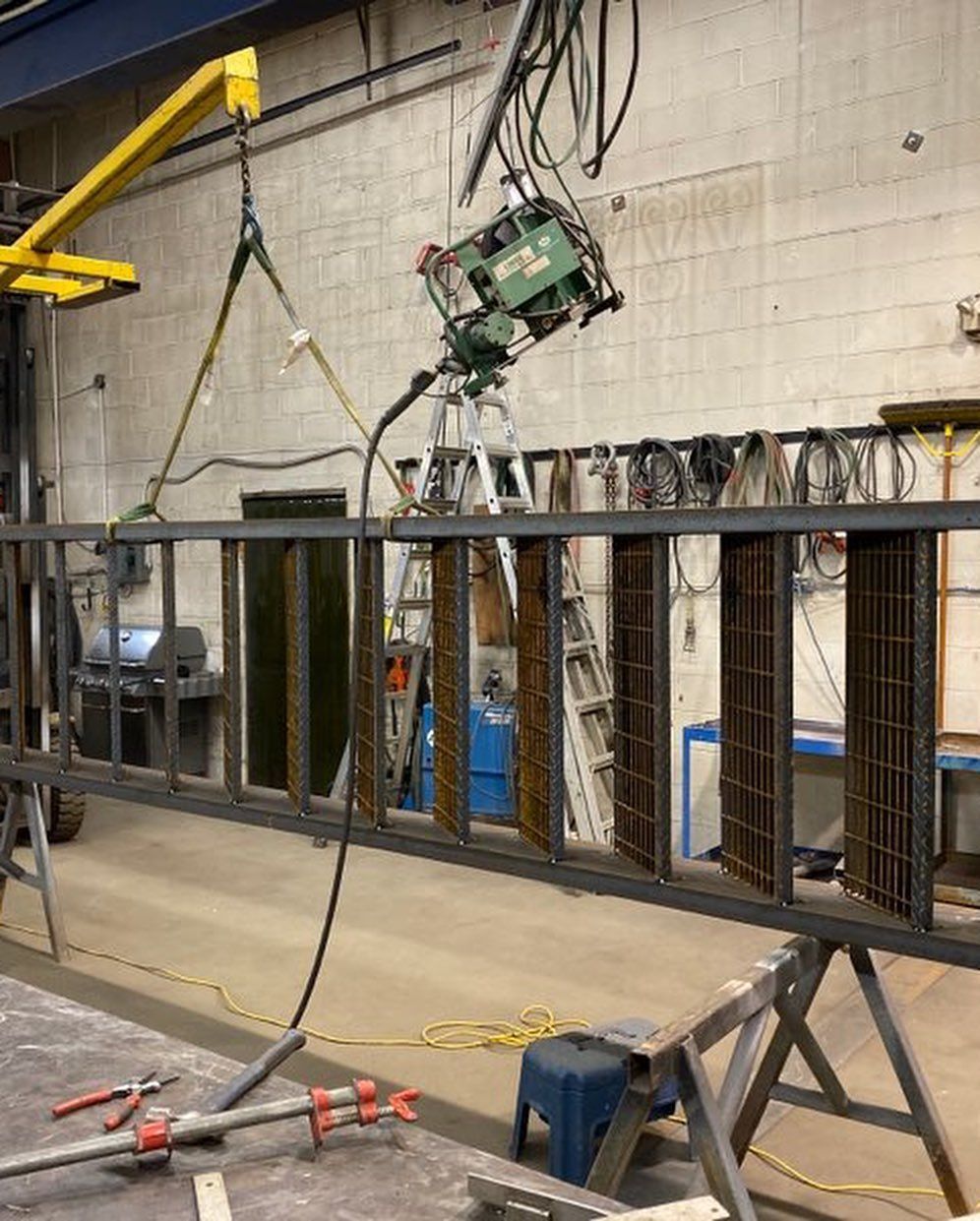 A ladder is being lifted by a crane in a factory.