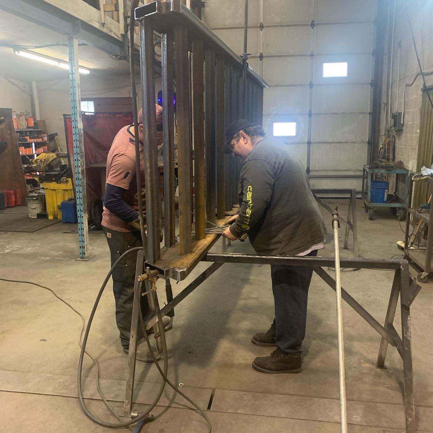 Two men are working on a piece of metal in a garage