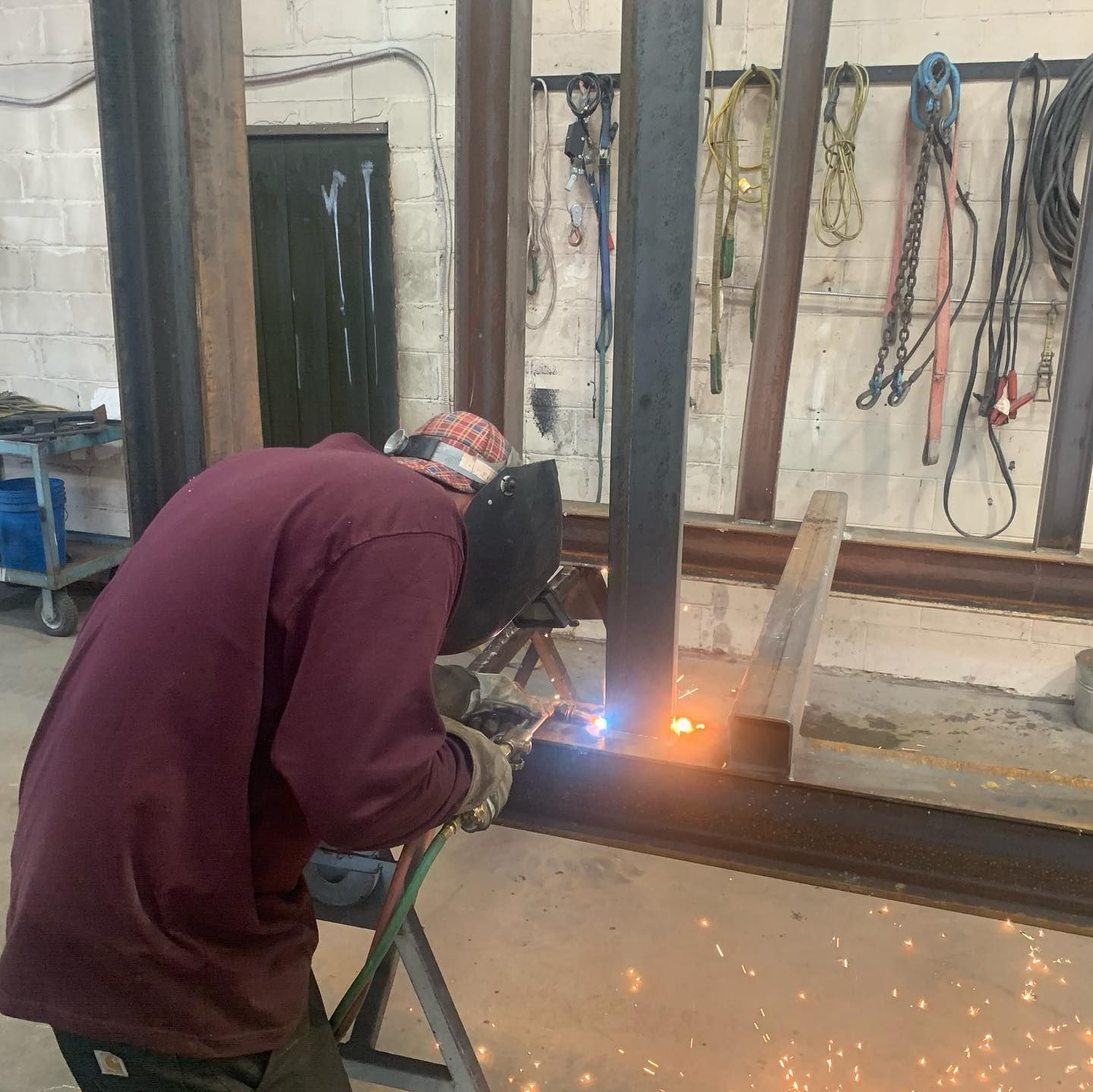 A man is welding a piece of metal in a workshop.