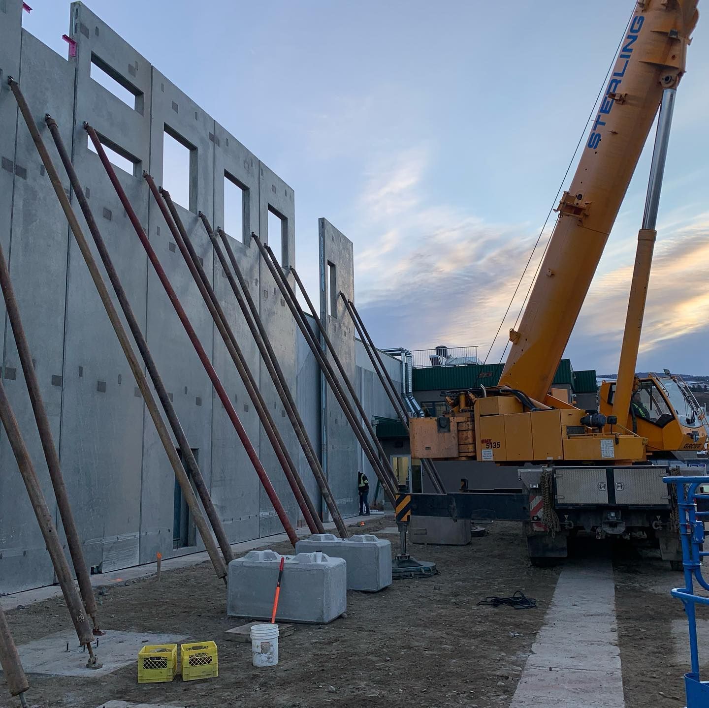 A large yellow crane is sitting in front of a building under construction