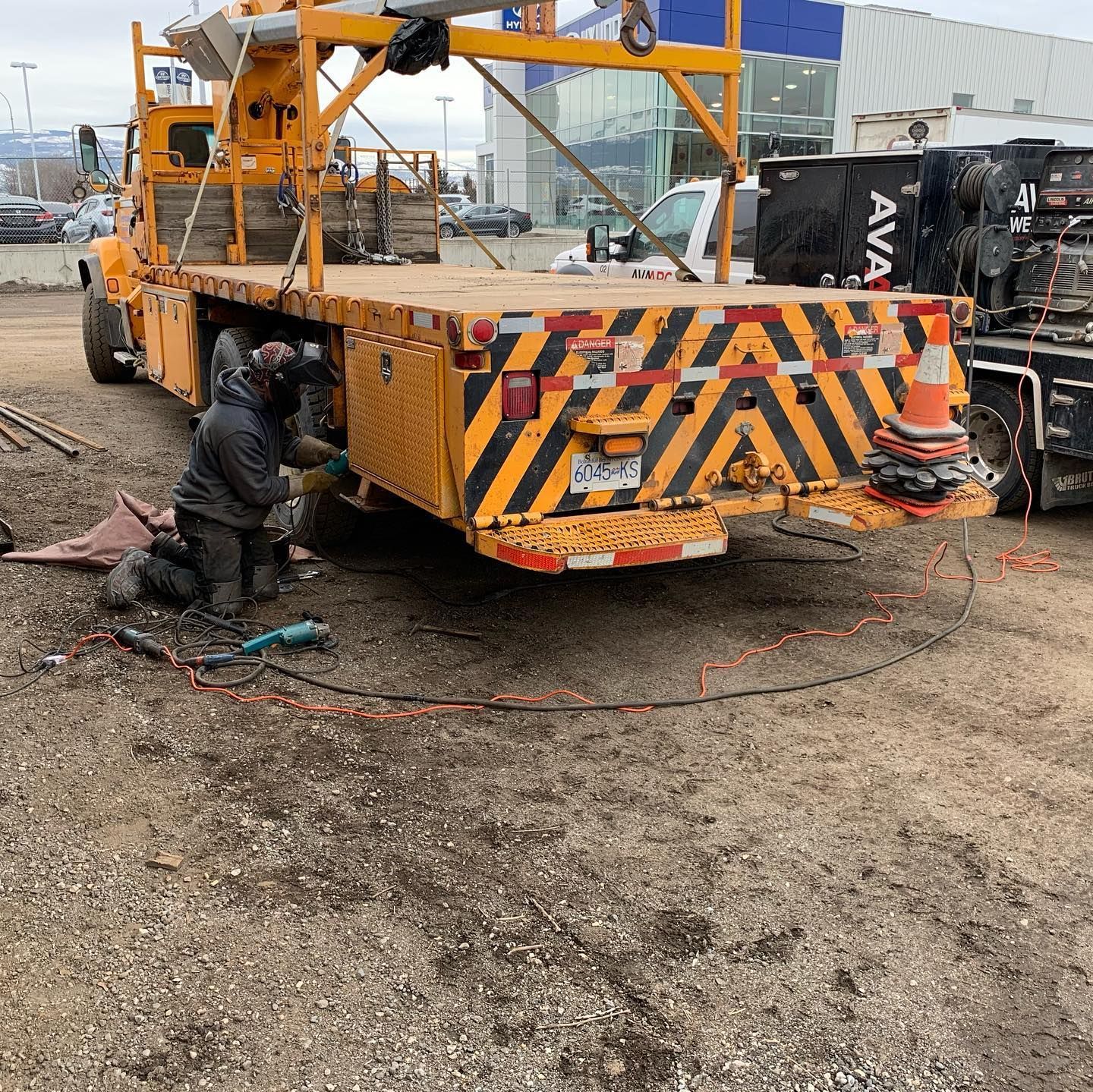 A man is working on the back of a yellow and black truck.