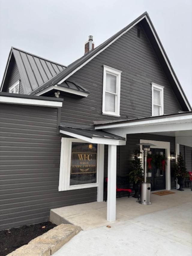 The front door of a house with a porch and plants in front of it.