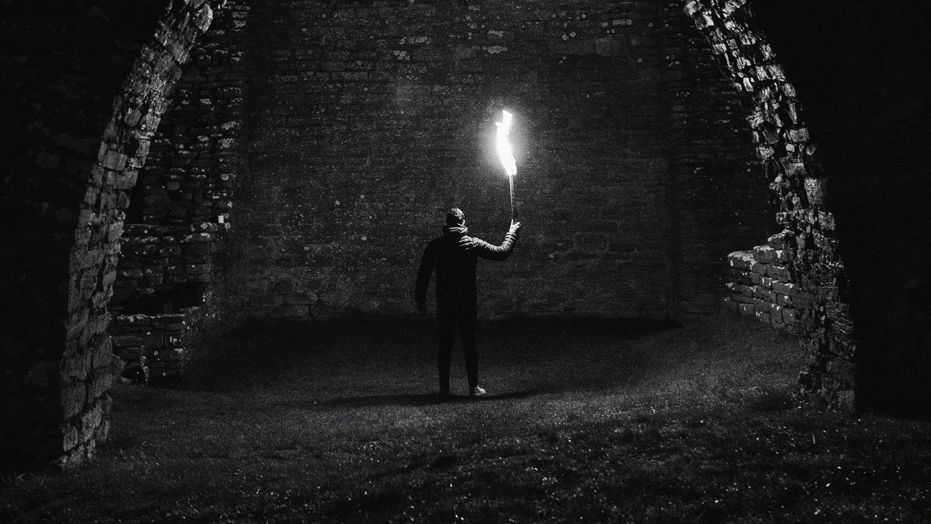 man holding a torch looking at a wall