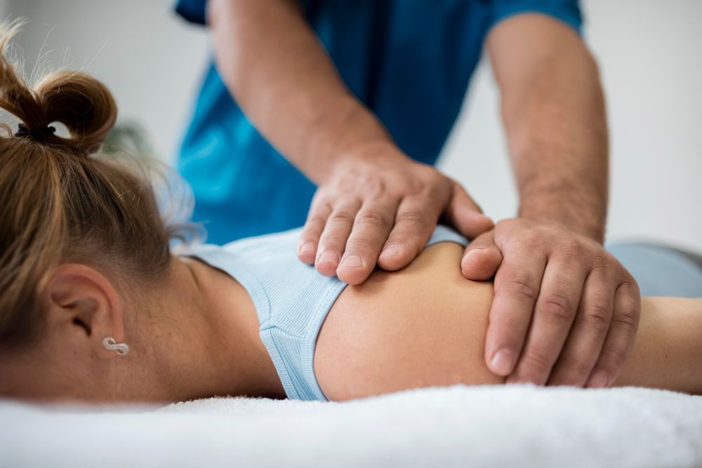 Person receiving a massage, therapist's hands on shoulder and back.