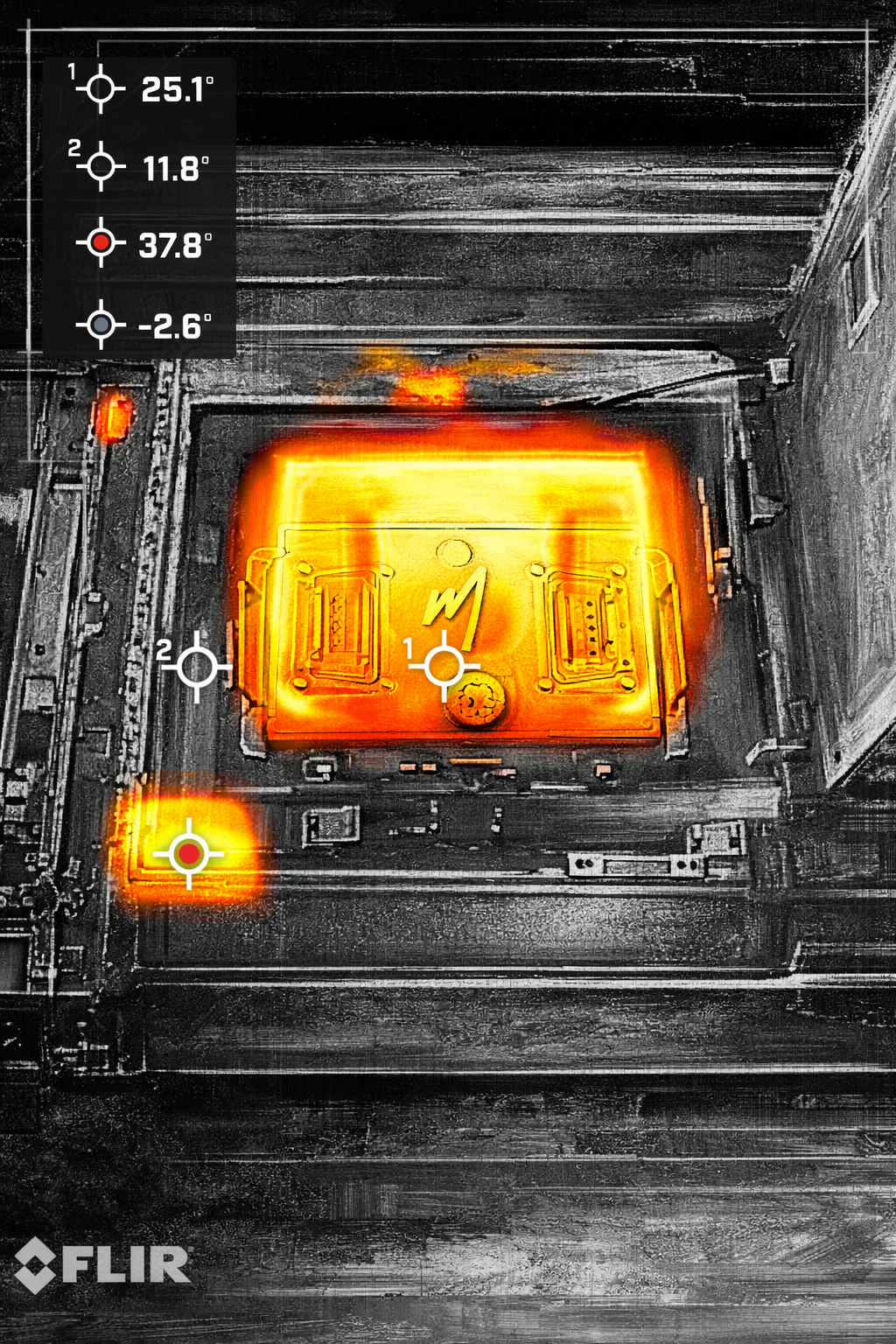 Thermal image of a hot machine, showing high temperature areas in orange against a gray background with temperature readings.