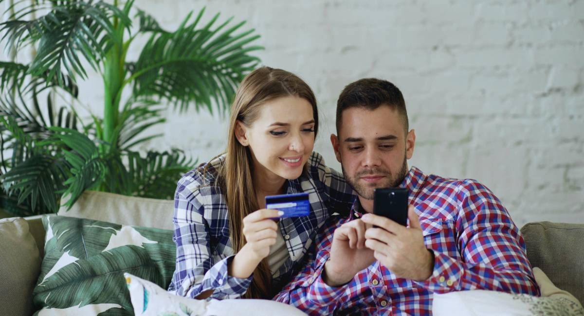 A couple sitting on a couch setting up a direct direct on their phone
