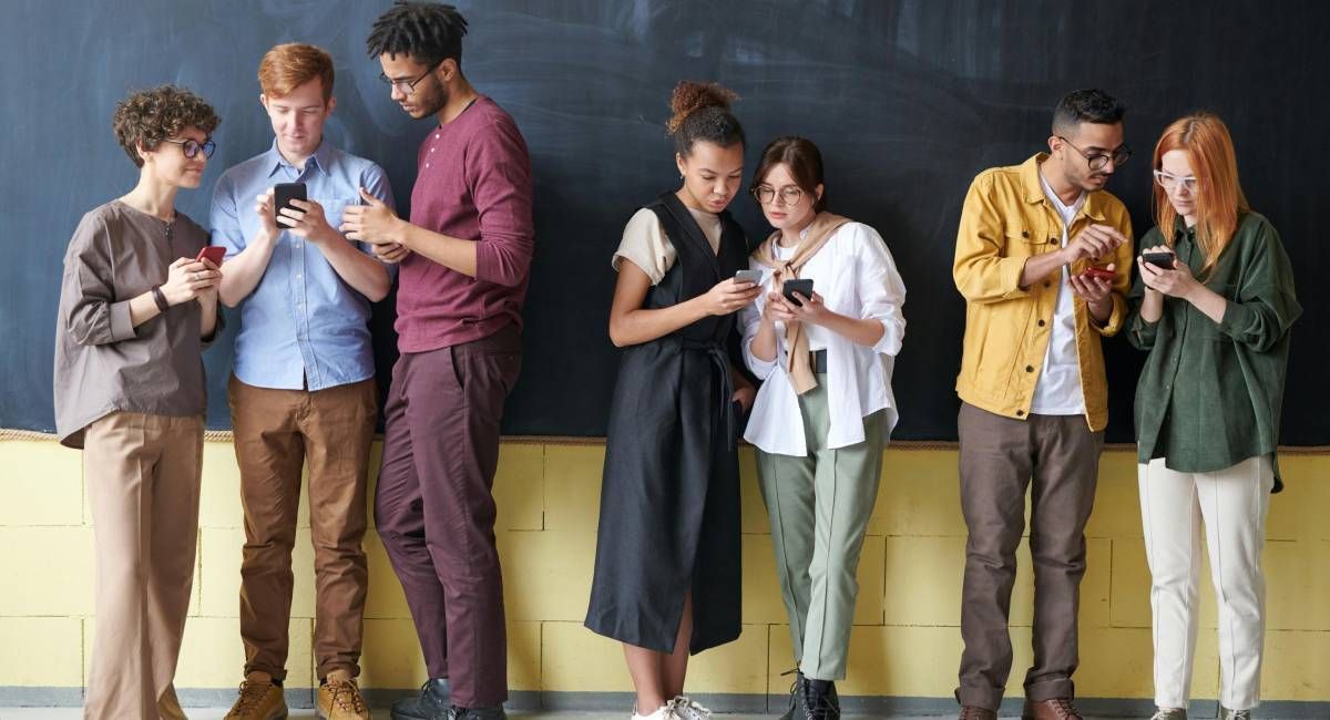 A group of young people interacting over something they are viewing on their phones