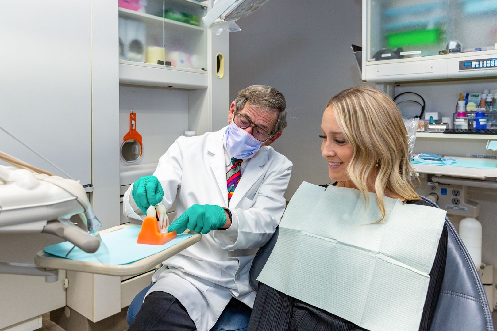 A man is sitting in a dental chair talking to a female dentist.