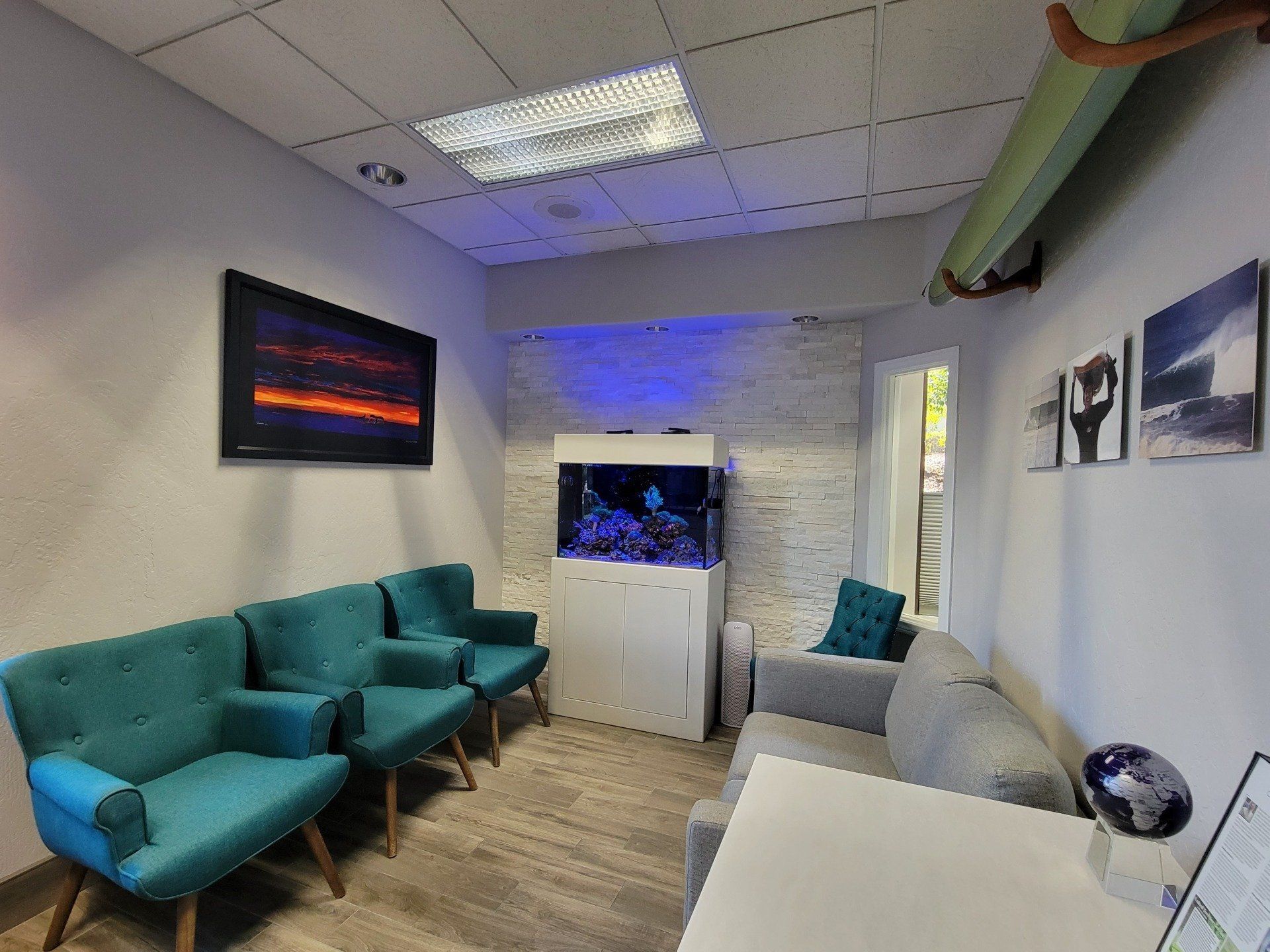 A waiting room with a couch , chairs , and an aquarium.