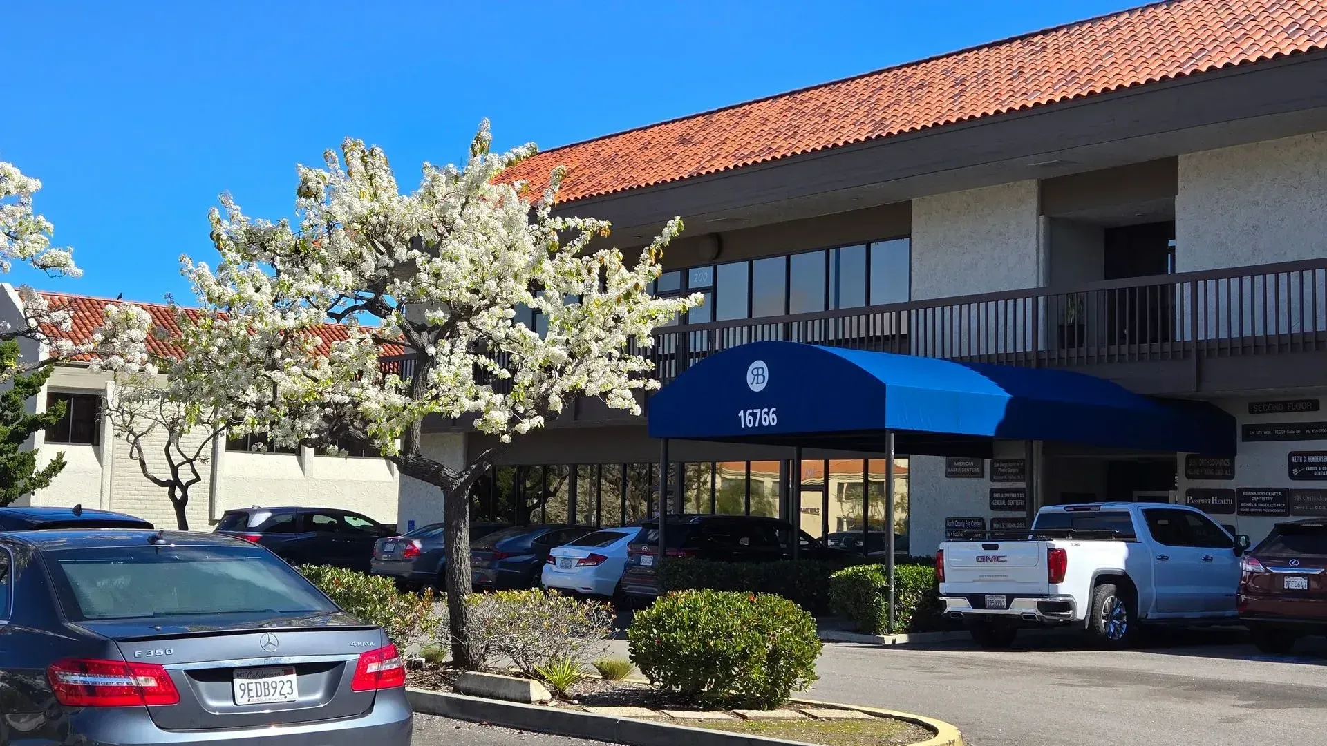Cars are parked in front of a building with a blue awning