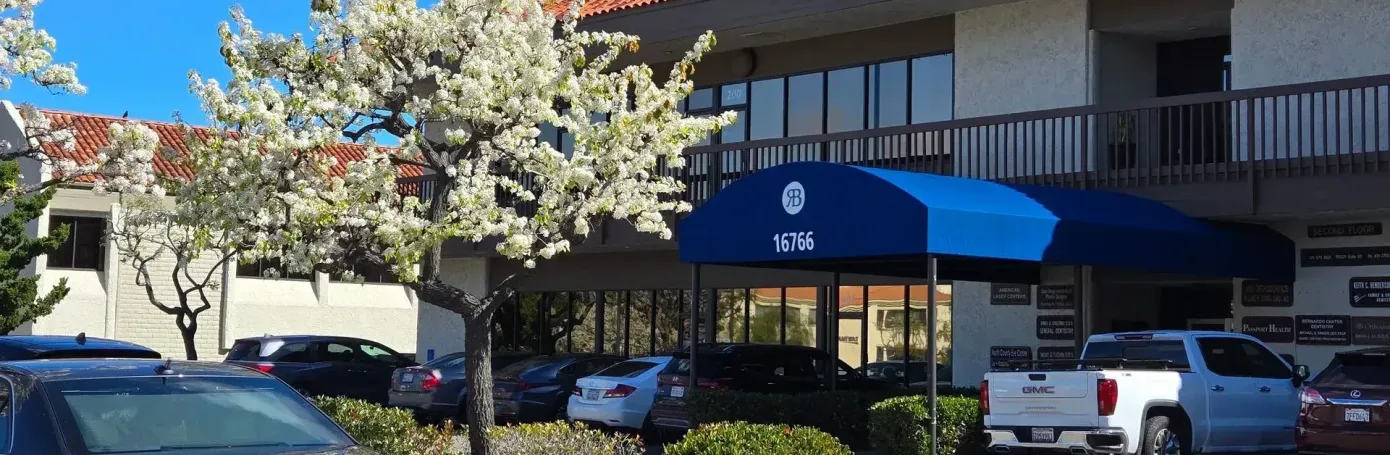 A white truck is parked in front of a building with a blue awning.