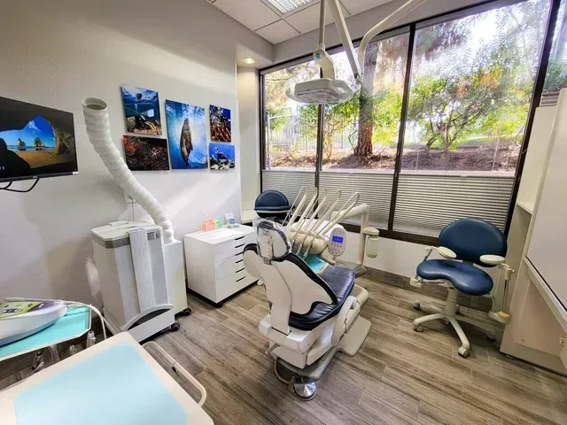 A dental office with a dental chair and a television on the wall.